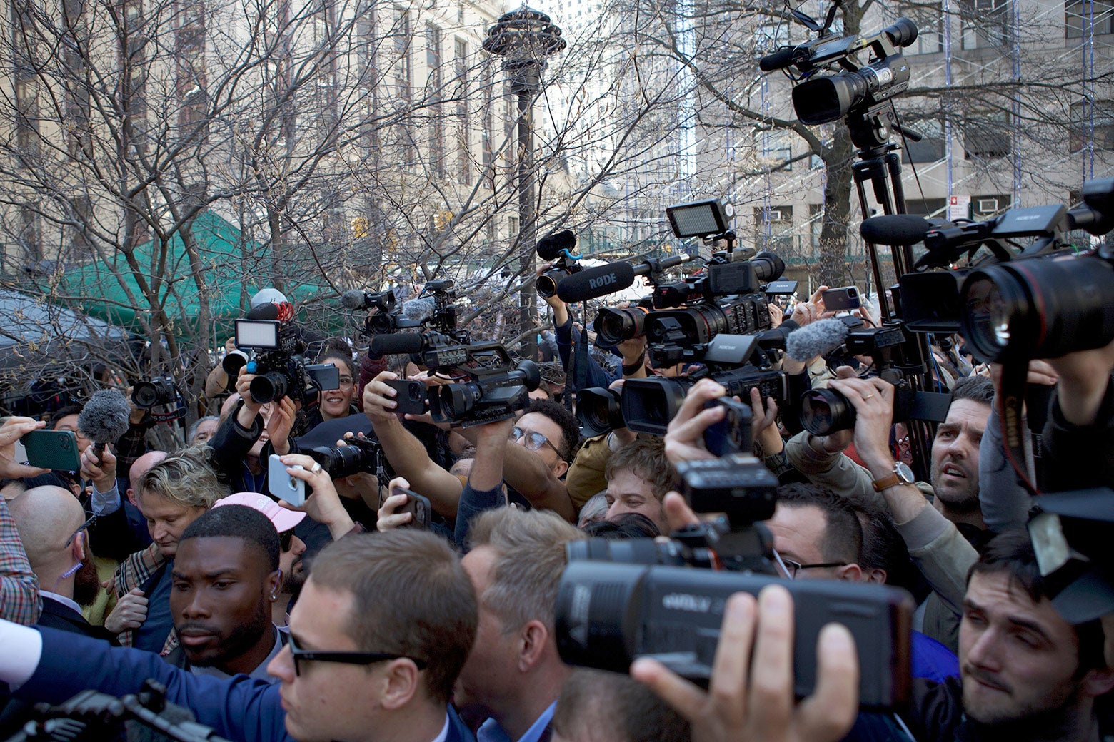 A busy scrum of reporters with cameras outside of a courthouse.