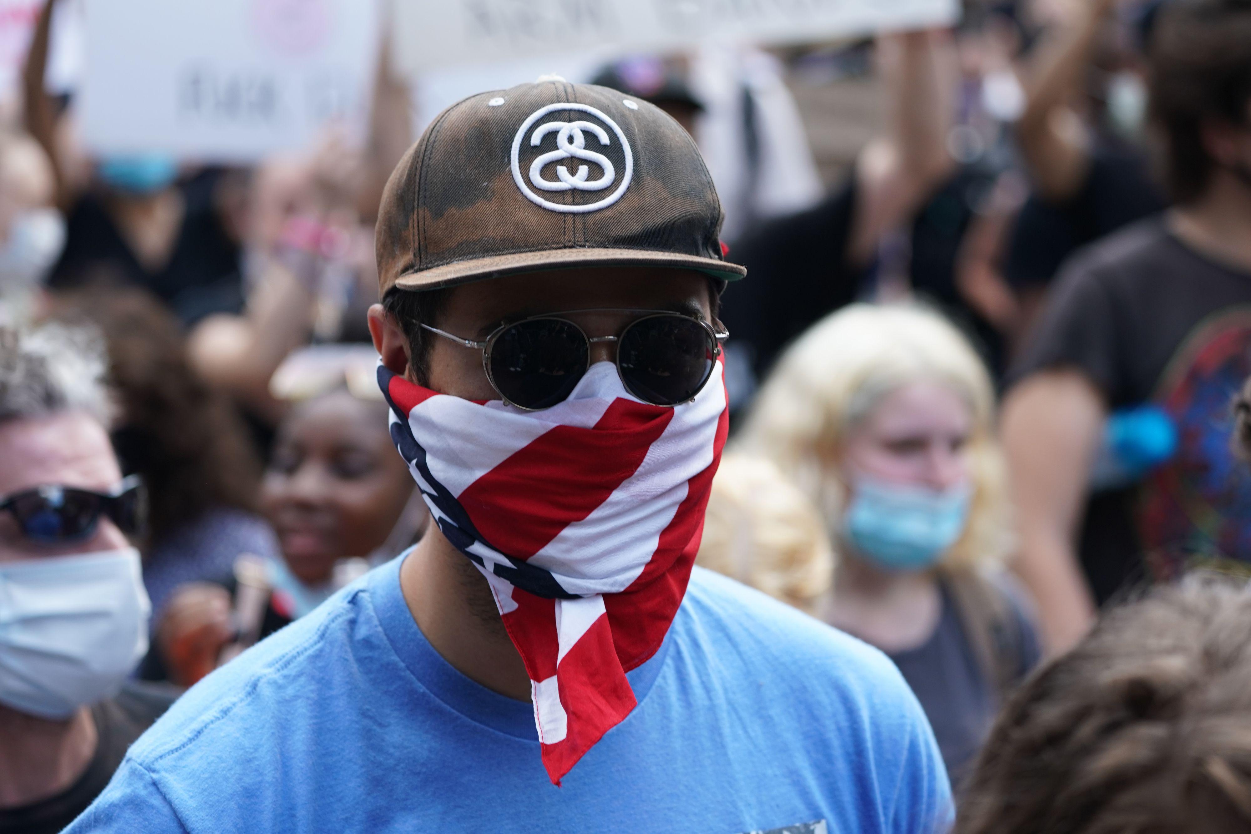 A protester wears a face mask that looks like an American flag.