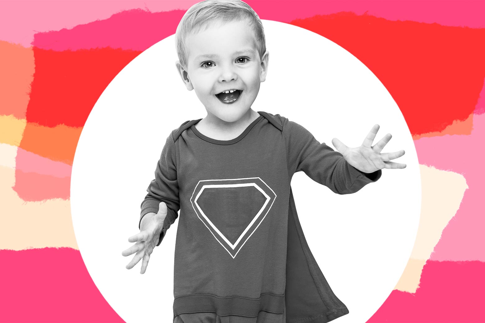 Toddler boy grinning in a superhero cape