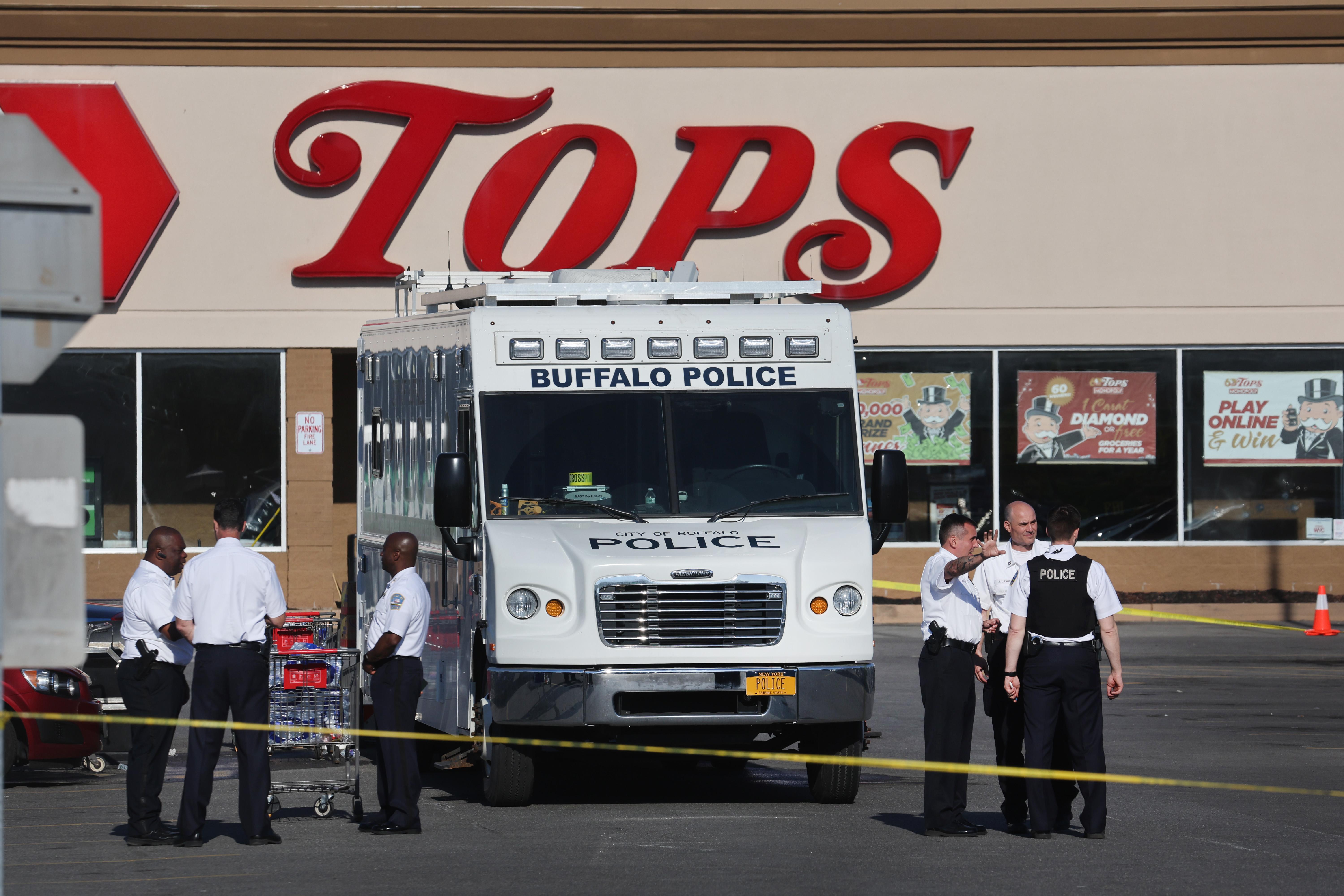 A Tops grocery store with a white police truck, police officers, and yellow police tape outside