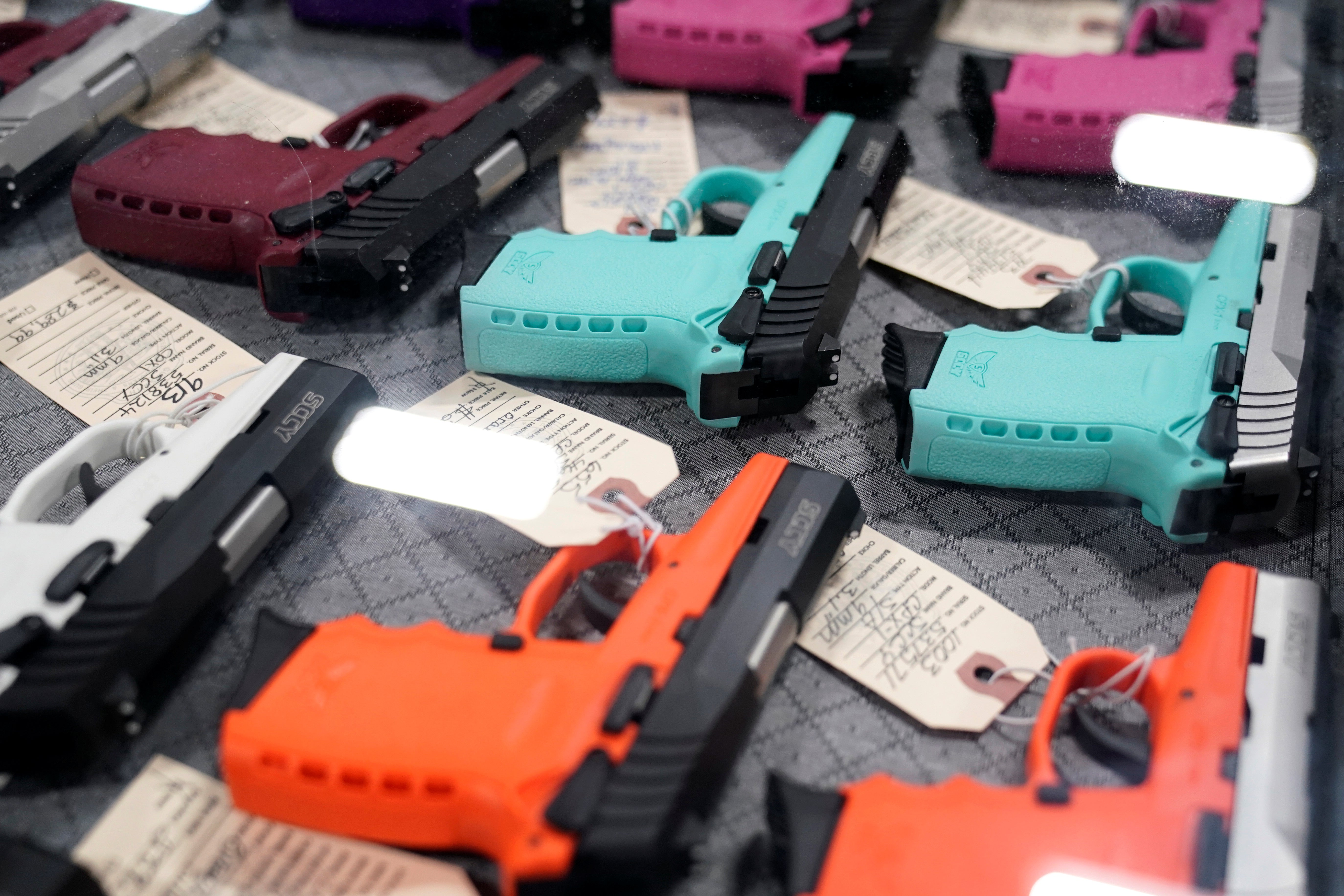 Pistols with colored grips arrayed on a table