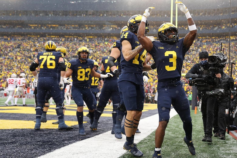 A Michigan football players raises his arms in celebration.