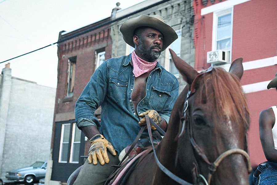 Two Black men ride horses through the streets of Philadelphia.