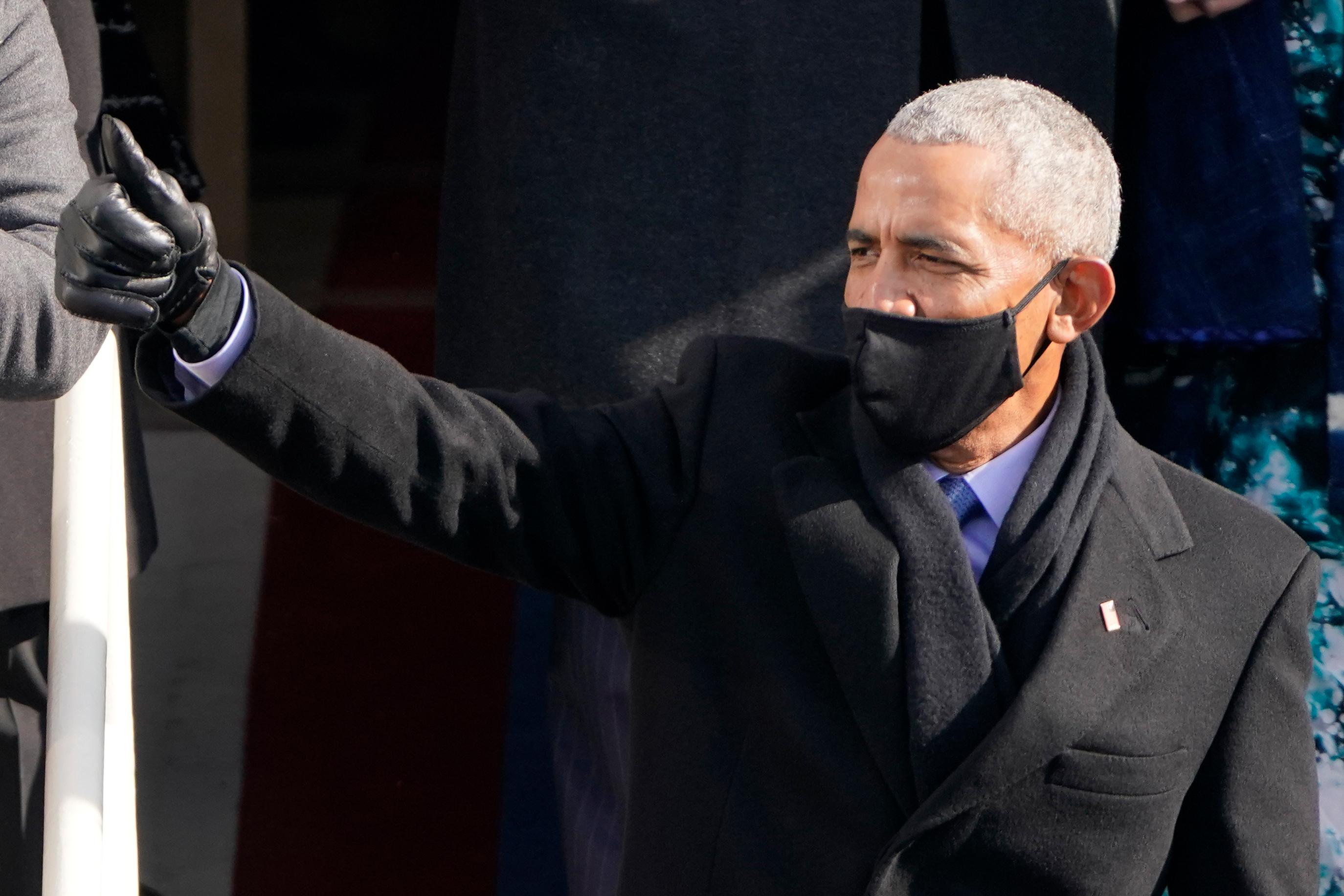 Obama wears a face mask and flashes a thumbs-up.