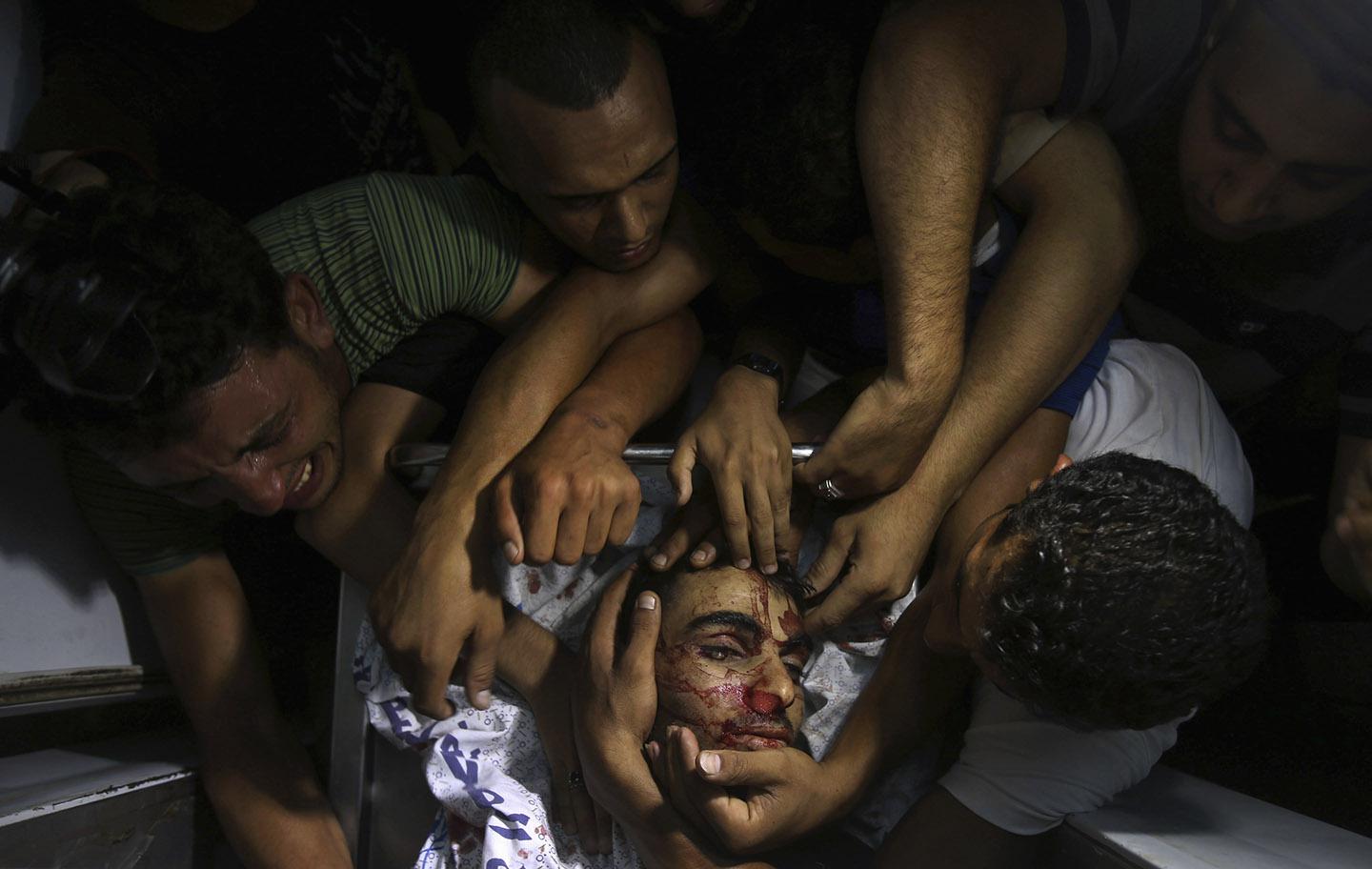 People mourn around the body of a Palestinian militant at a hospital morgue in the central Gaza Strip July 6, 2014.