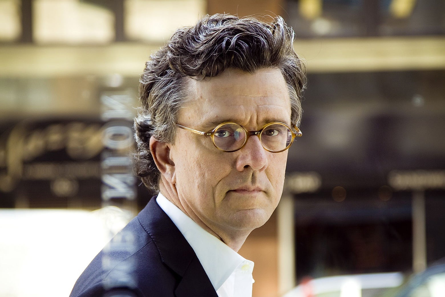 A middle-aged white man with small glasses and curly hair.