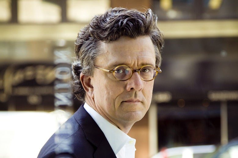 A middle-aged white man with small glasses and curly hair.