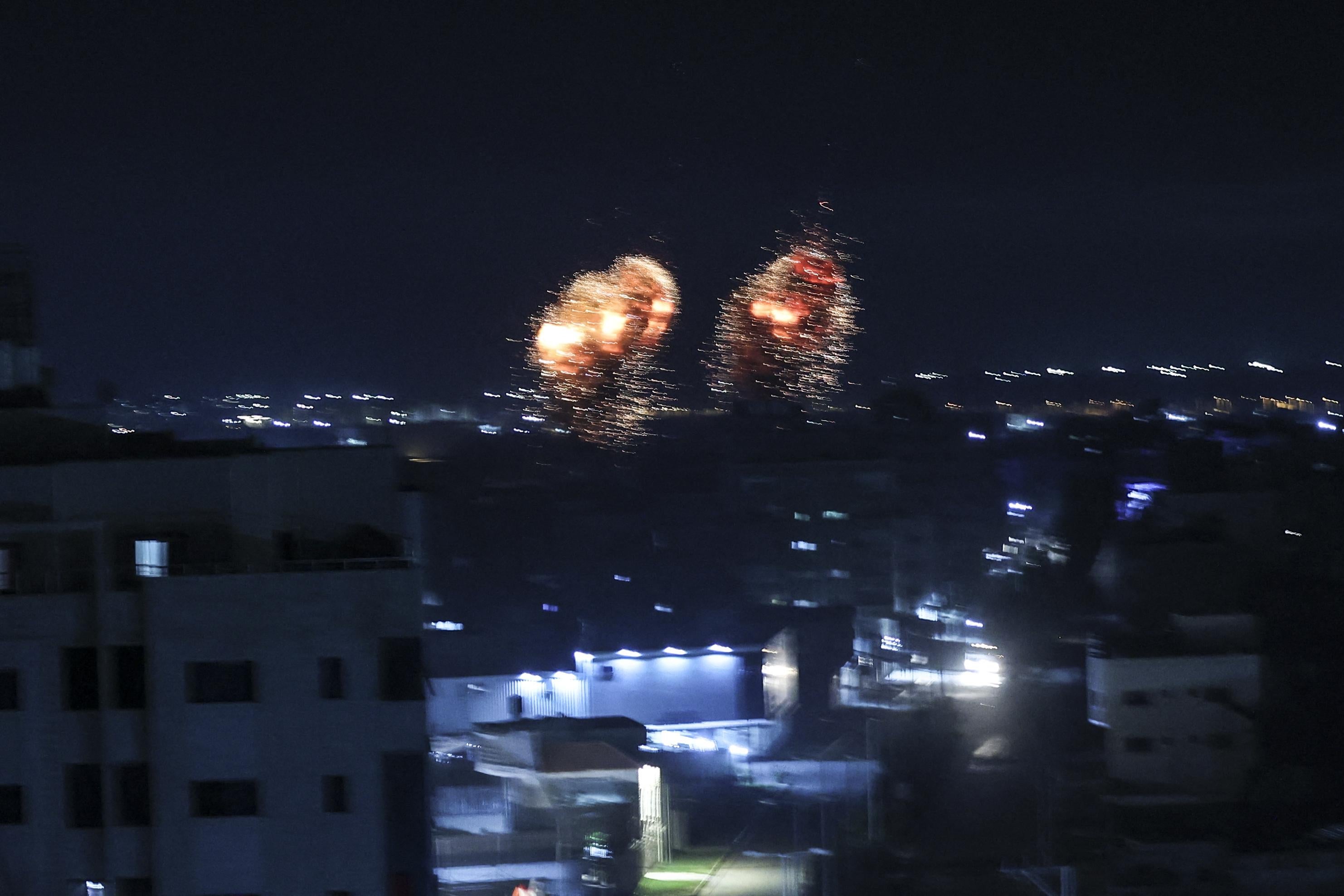 Two fiery explosions can be seen in the night sky on Gaza city skyline.