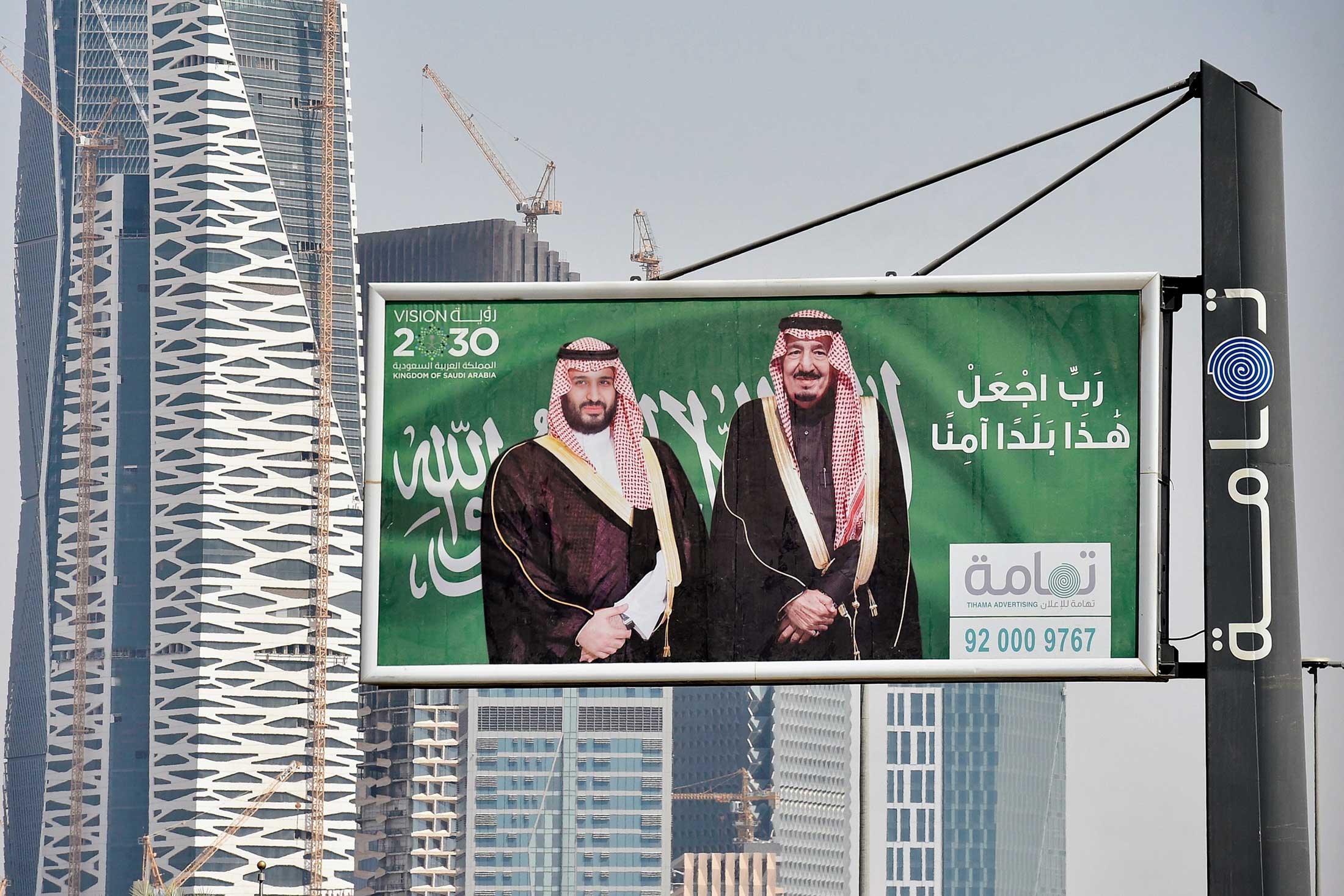 Portraits of Saudi Arabian King Salman and his son, Crown Prince Mohammed Bin Salman, on a printed sign