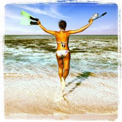 Joyful woman in bikini runs to the sea