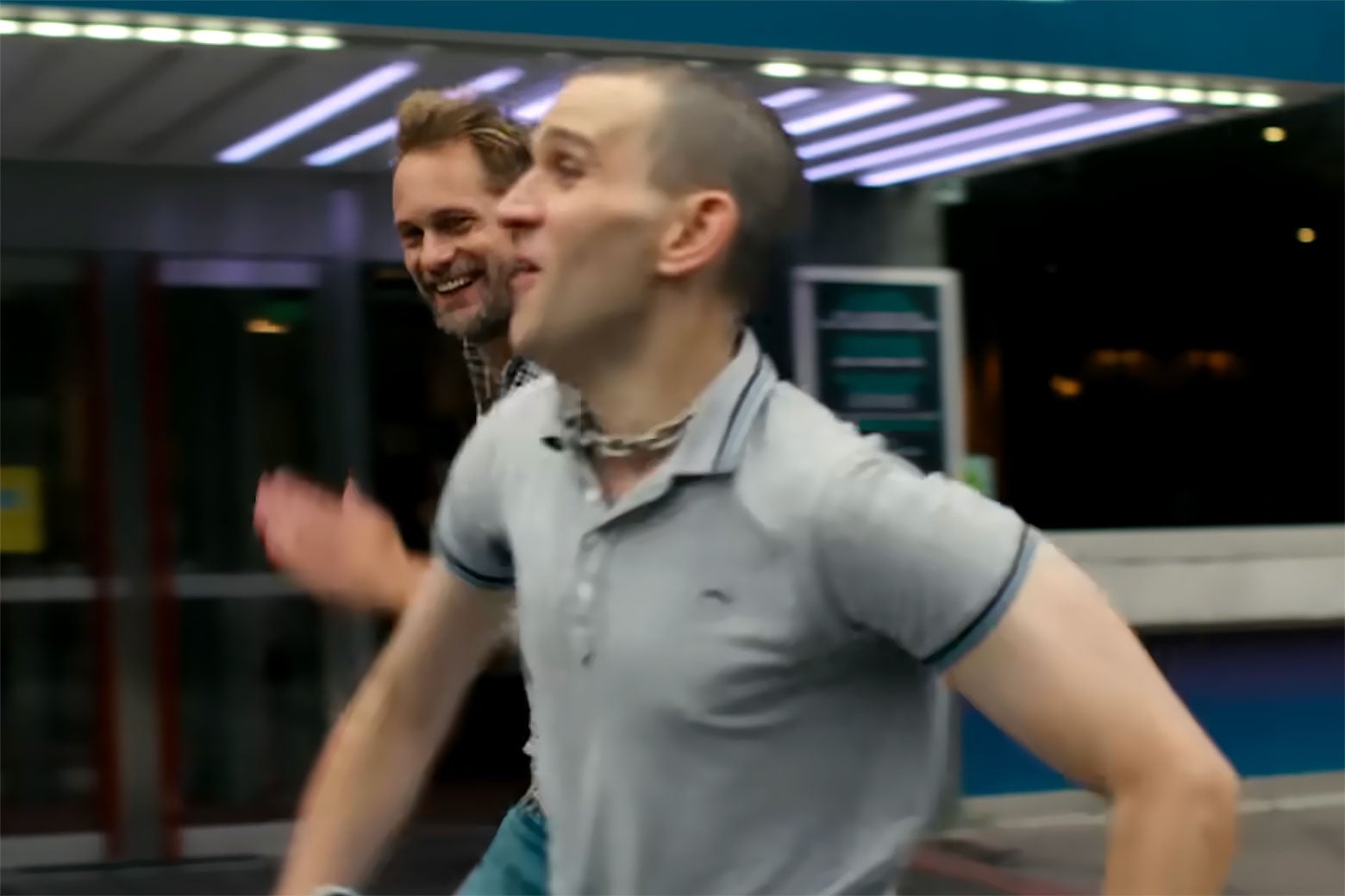 Two men happily racing each other down a street.