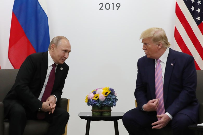 Putin and Trump, seated side-by-side, lean in to speak to one another at a summit.