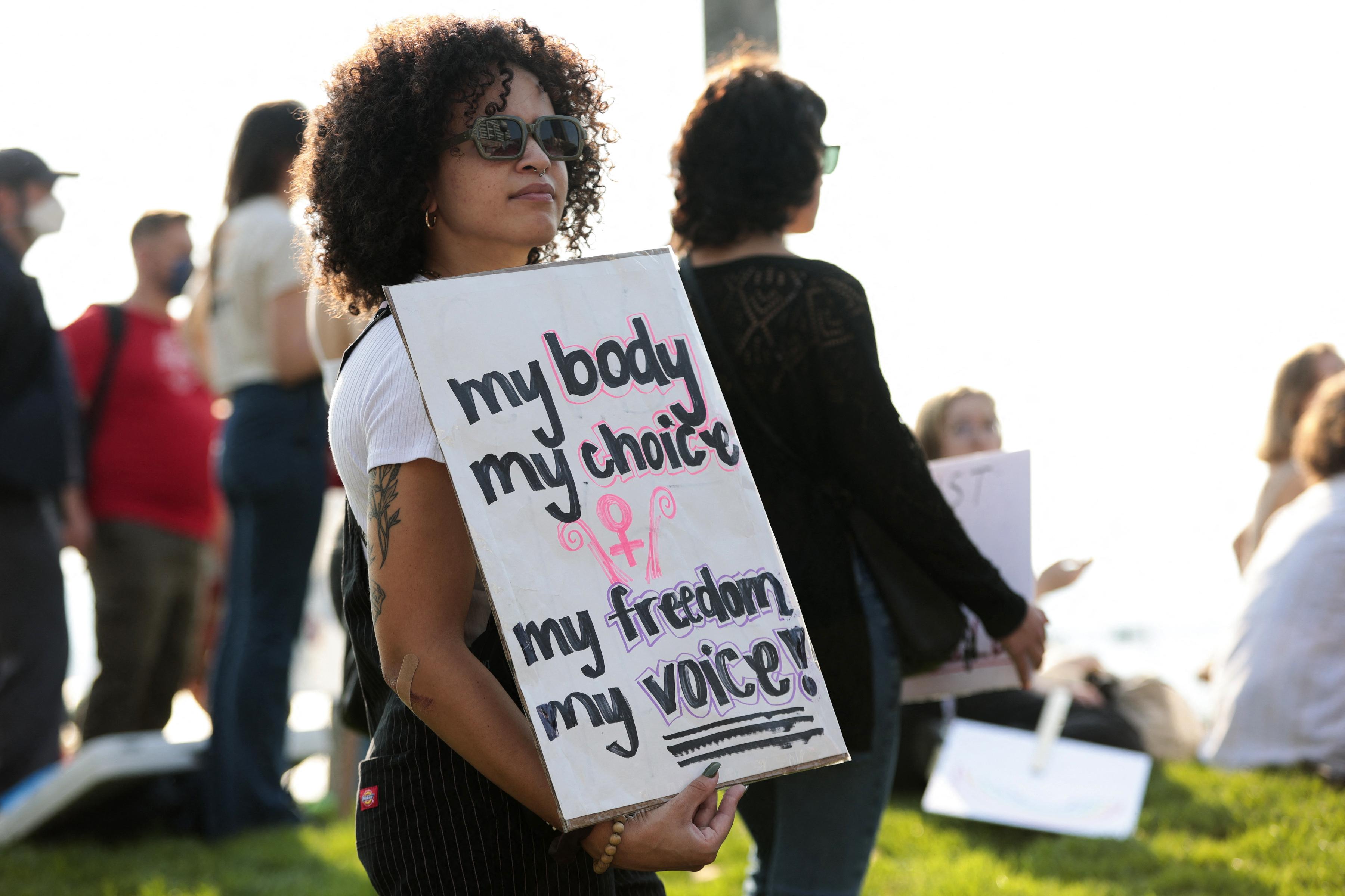 A woman stands outside holding a pro–abortion rights sign.