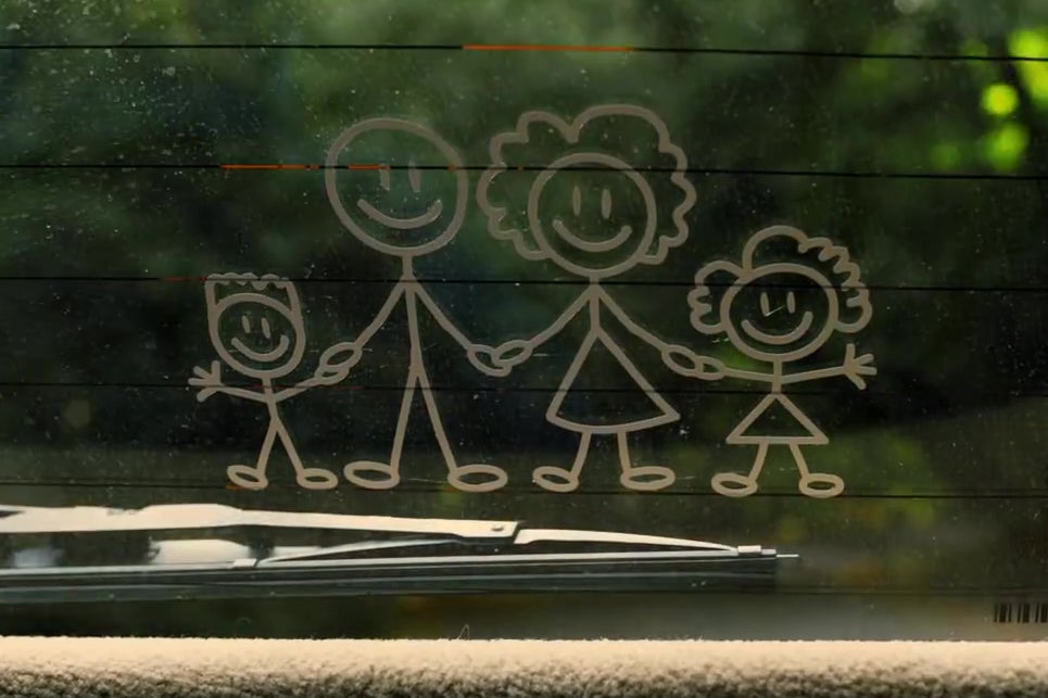 A still from Us depicting a car rear-window decal of a stick-figure family of four people,