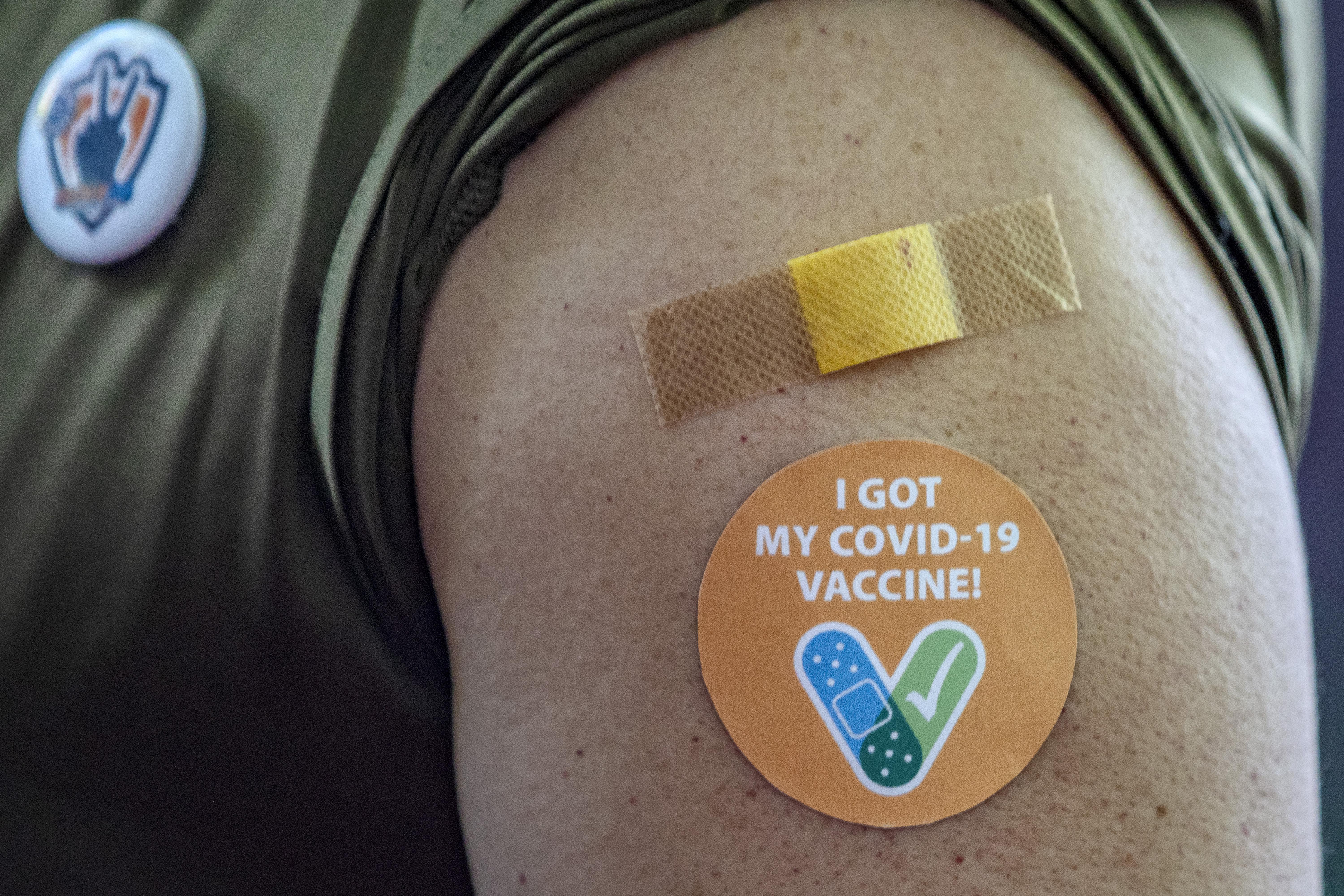 A person's arm with a Band-Aid and a sticker on it that says "I Got My COVID-19 Vaccine!"