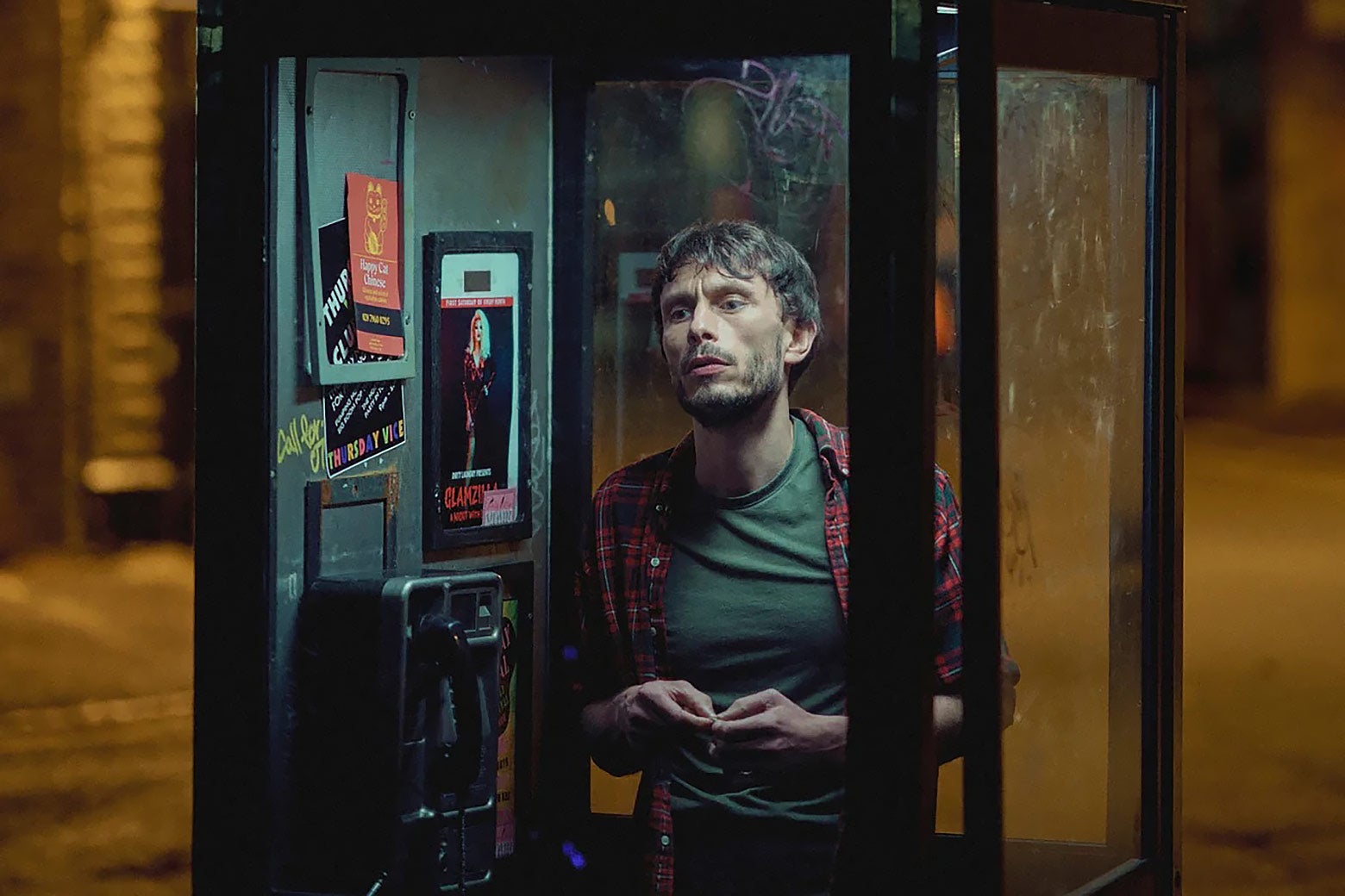 A man stands in a phone booth. 