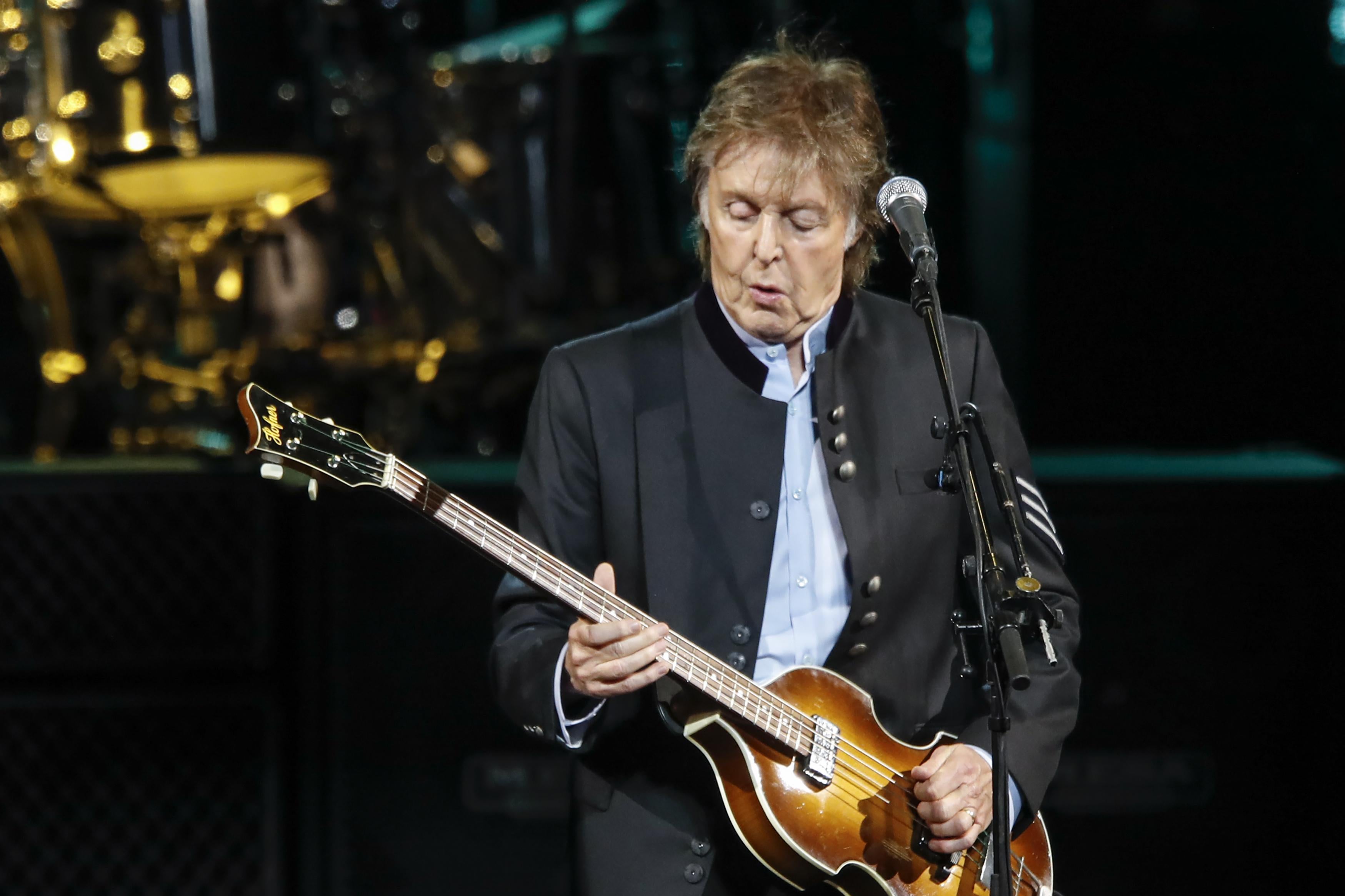 Paul McCartney plays a guitar onstage.