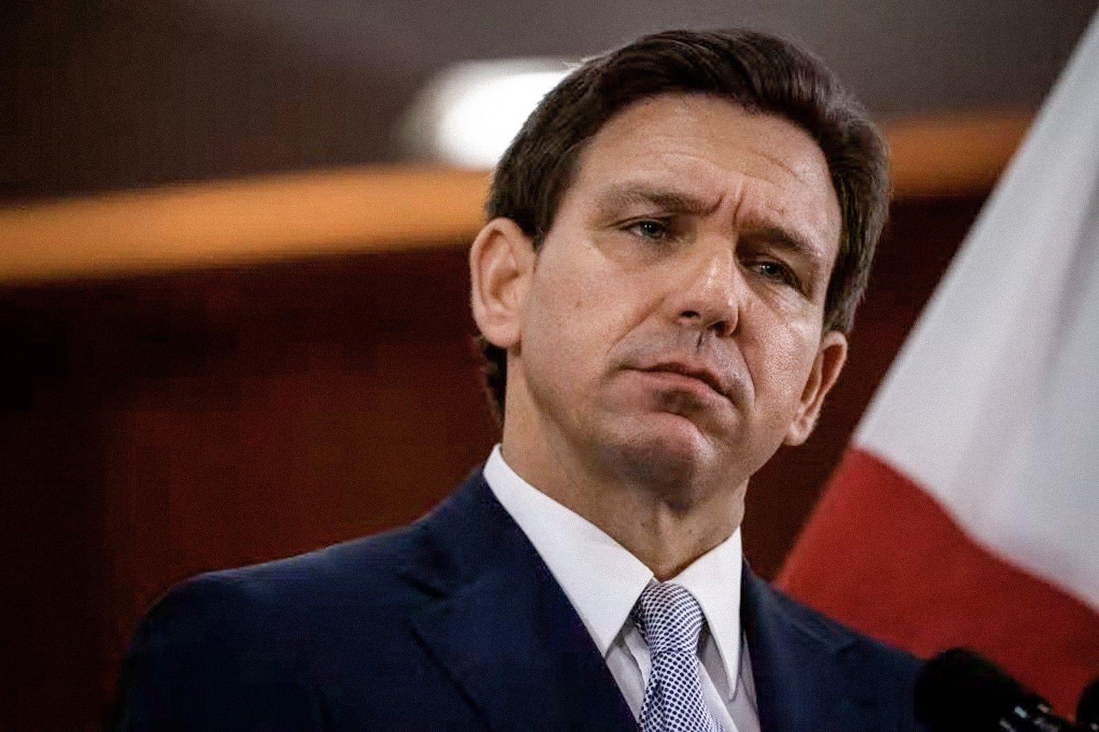 Ron DeSantis tilts his head to his left with a quizzical expression on his face at a press conference.