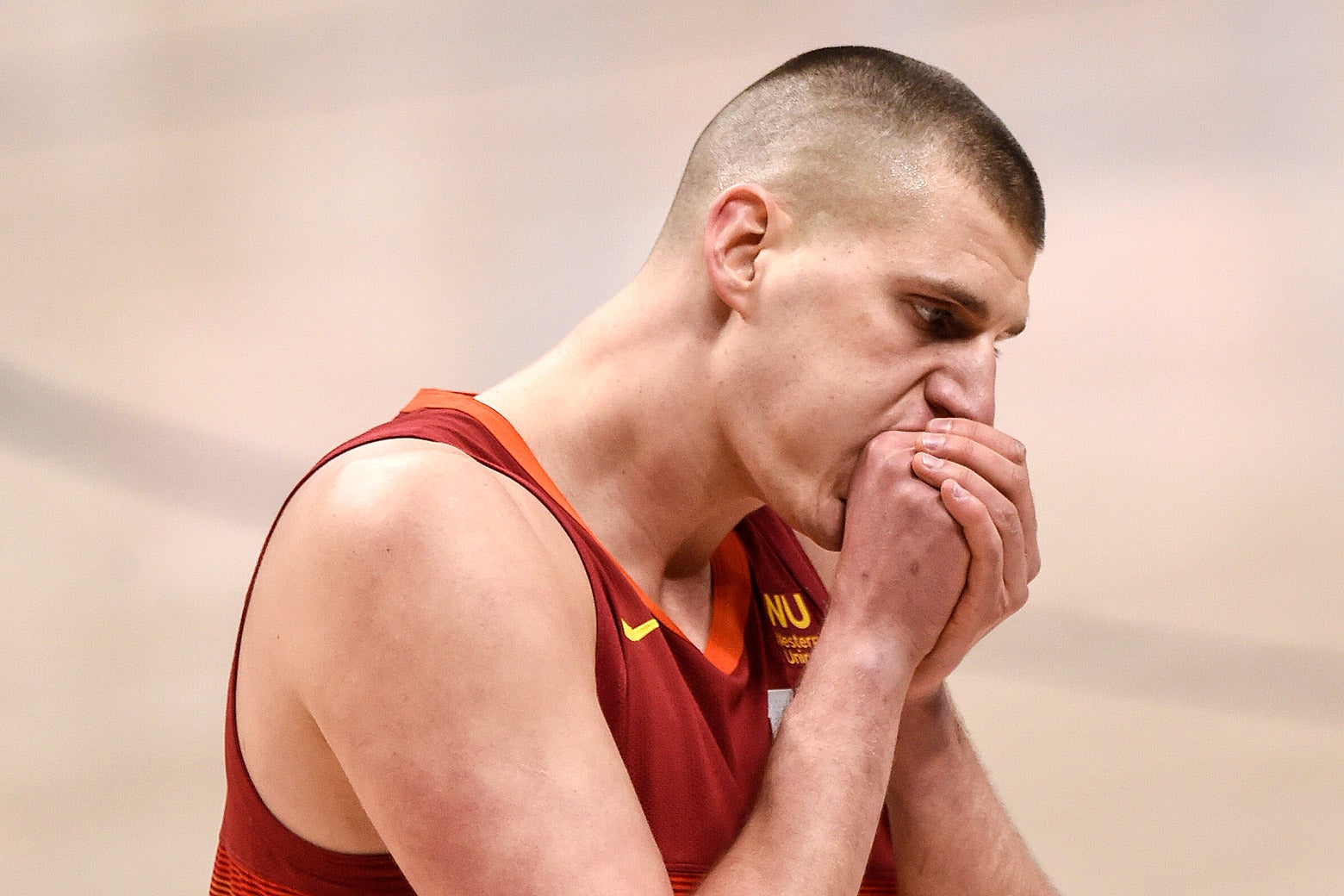 Jokić, wearing a red jersey, blows into his cupped hands during a game.