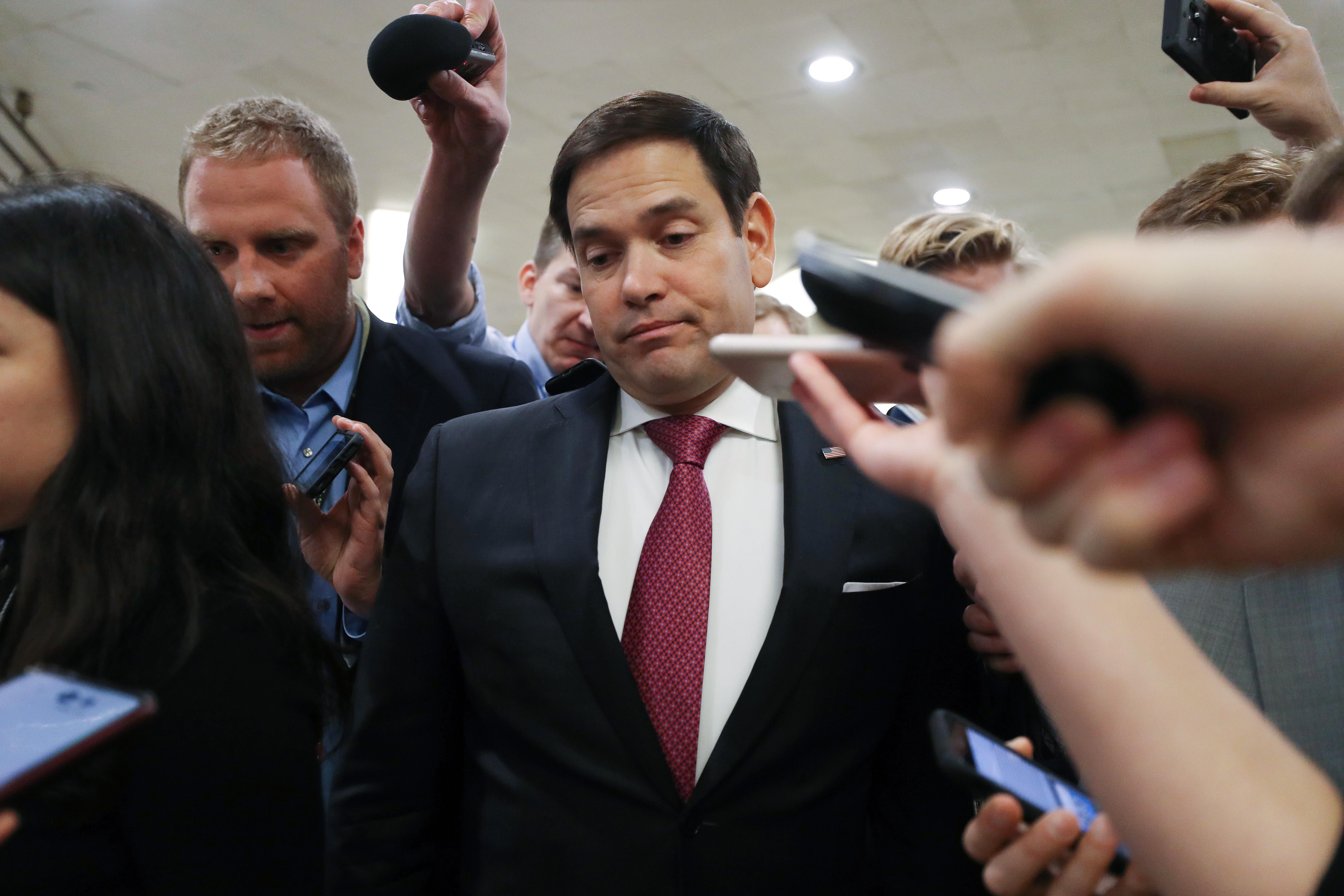 Marco Rubio surrounded by reporters looking down.
