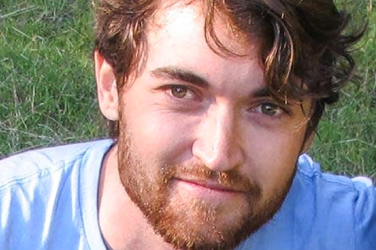Ross Ulbricht in a blue shirt, bearded, smiling.
