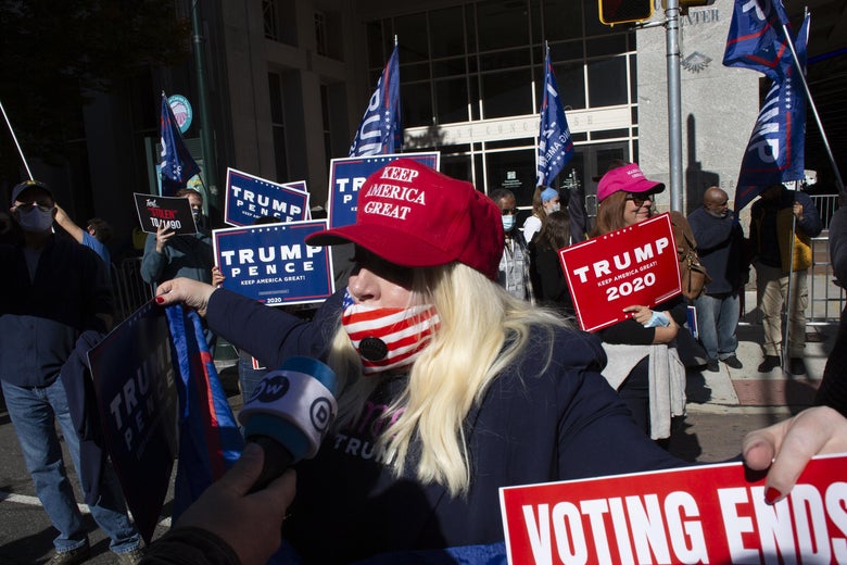 A woman in a MAGA hat and an American flag mask, which sits below her nose.