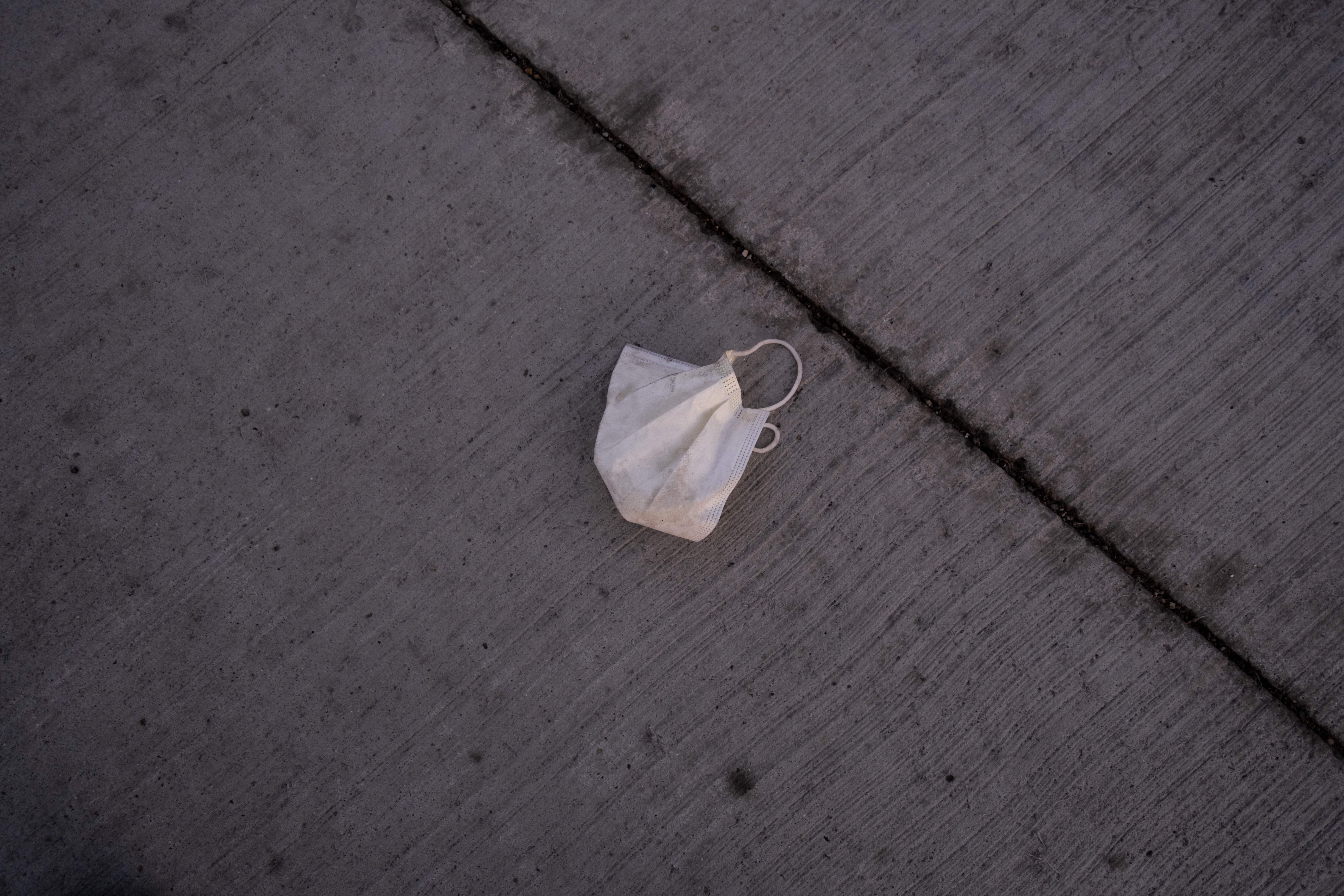 A medical mask is seen on the ground.