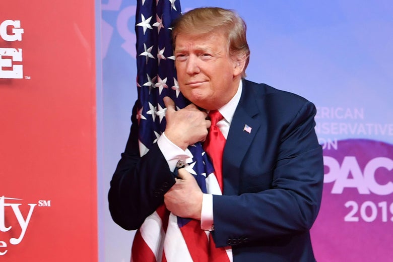 Trump hugs the U.S. flag as he arrives to speak onstage.