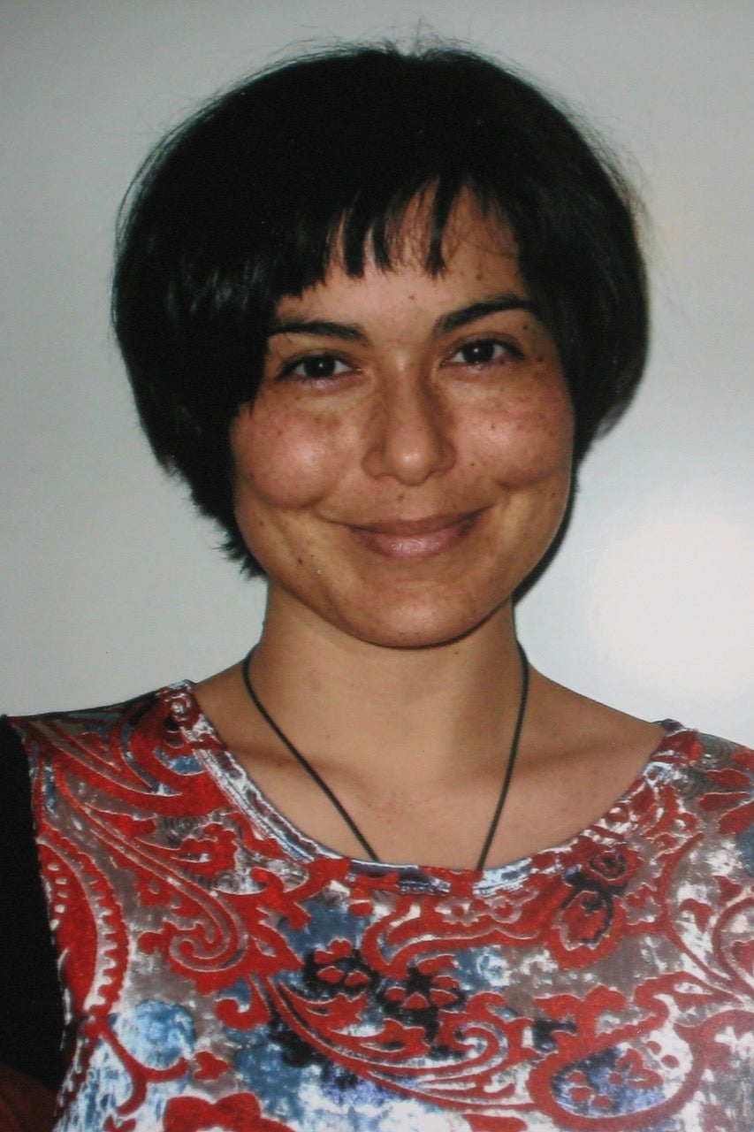 A portrait of a young woman with short black hair. She calmly smiles.