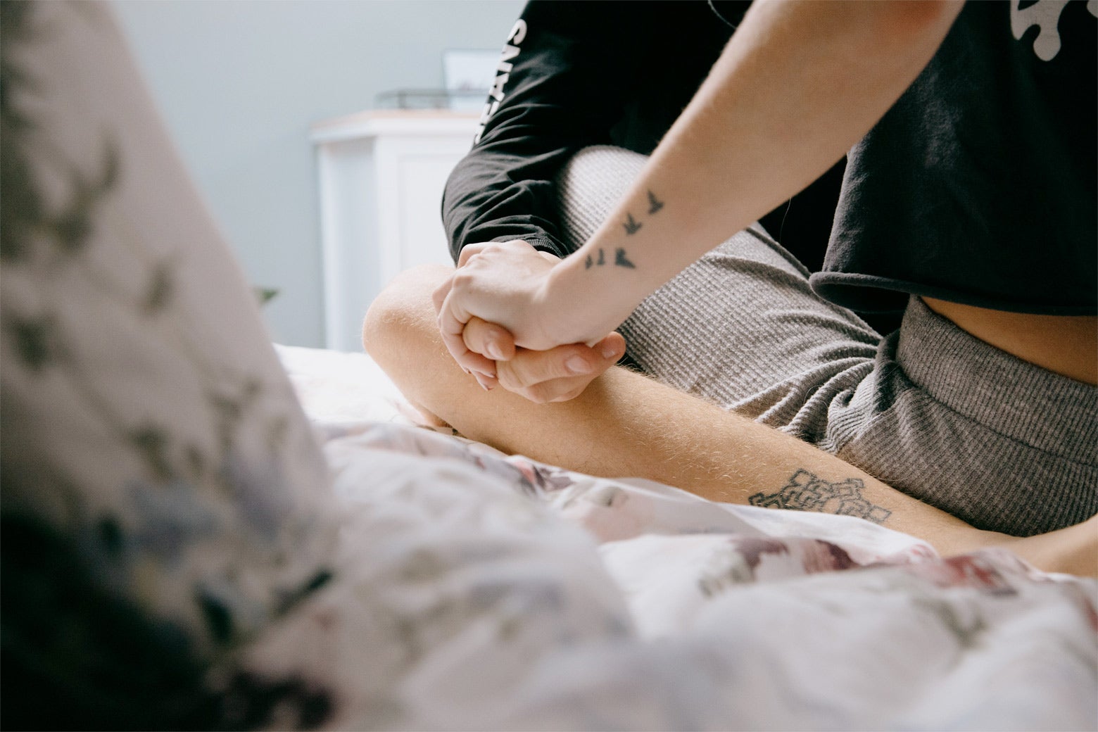 Two tattooed teens hold hands.