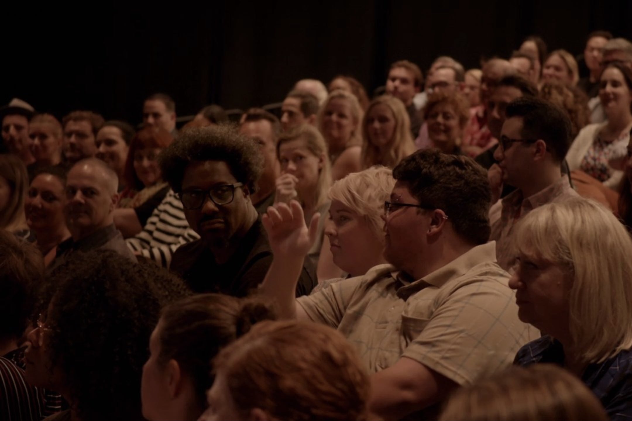 A theater audience. W. Kamau Bell and Gavin Grimm are seated towards the front; Susan Sarandon is visible in the back.
