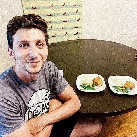 Jonny smiling, sitting next to two dinner plates on a table.