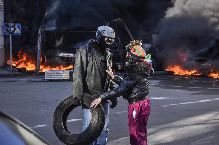 People speak near a barricade on fire during clashes between protesters and government police in Kiev on Feb. 18, 2014.