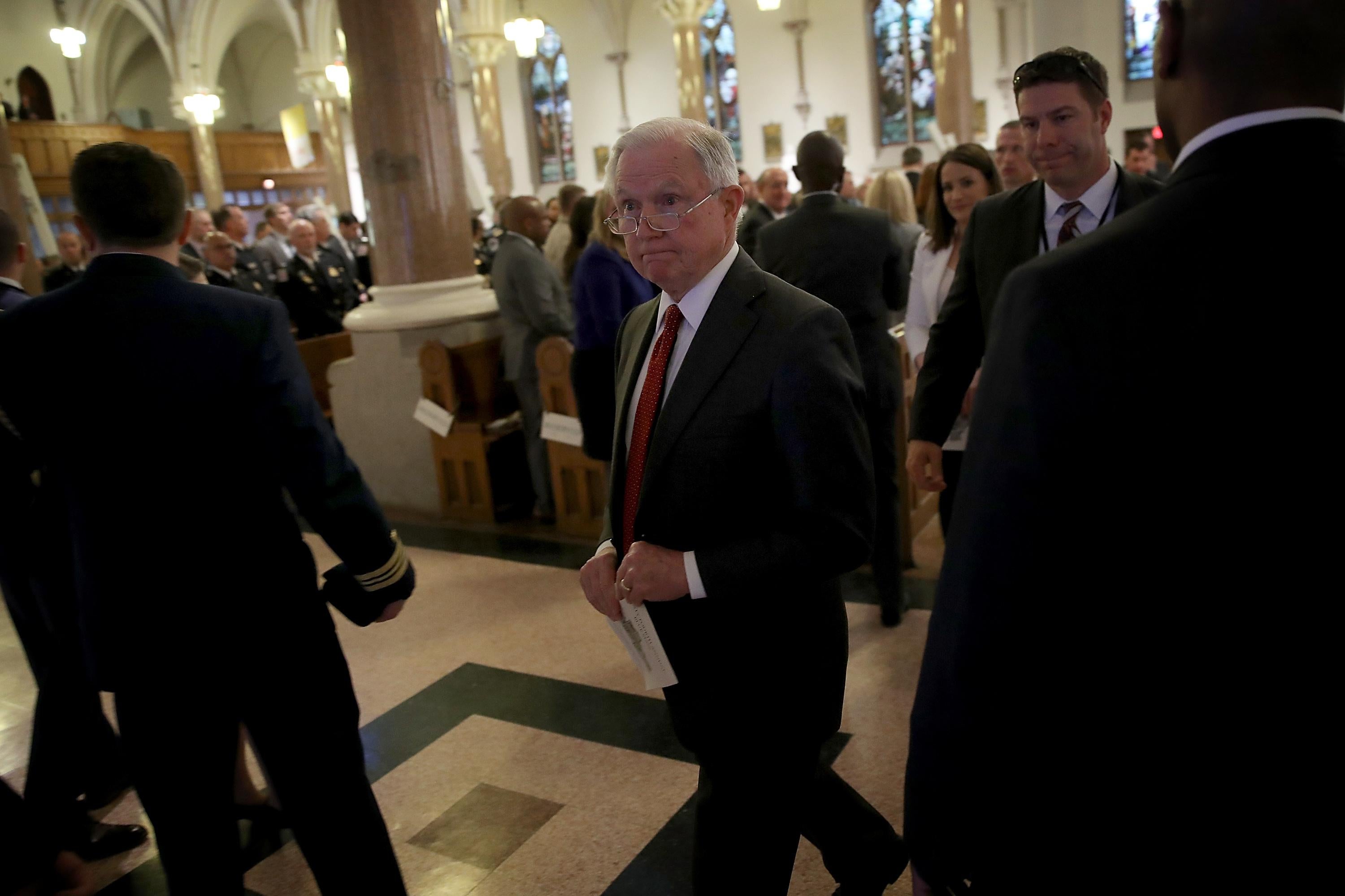 Jeff Sessions walking through a cathedral sanctuary with other worshippers