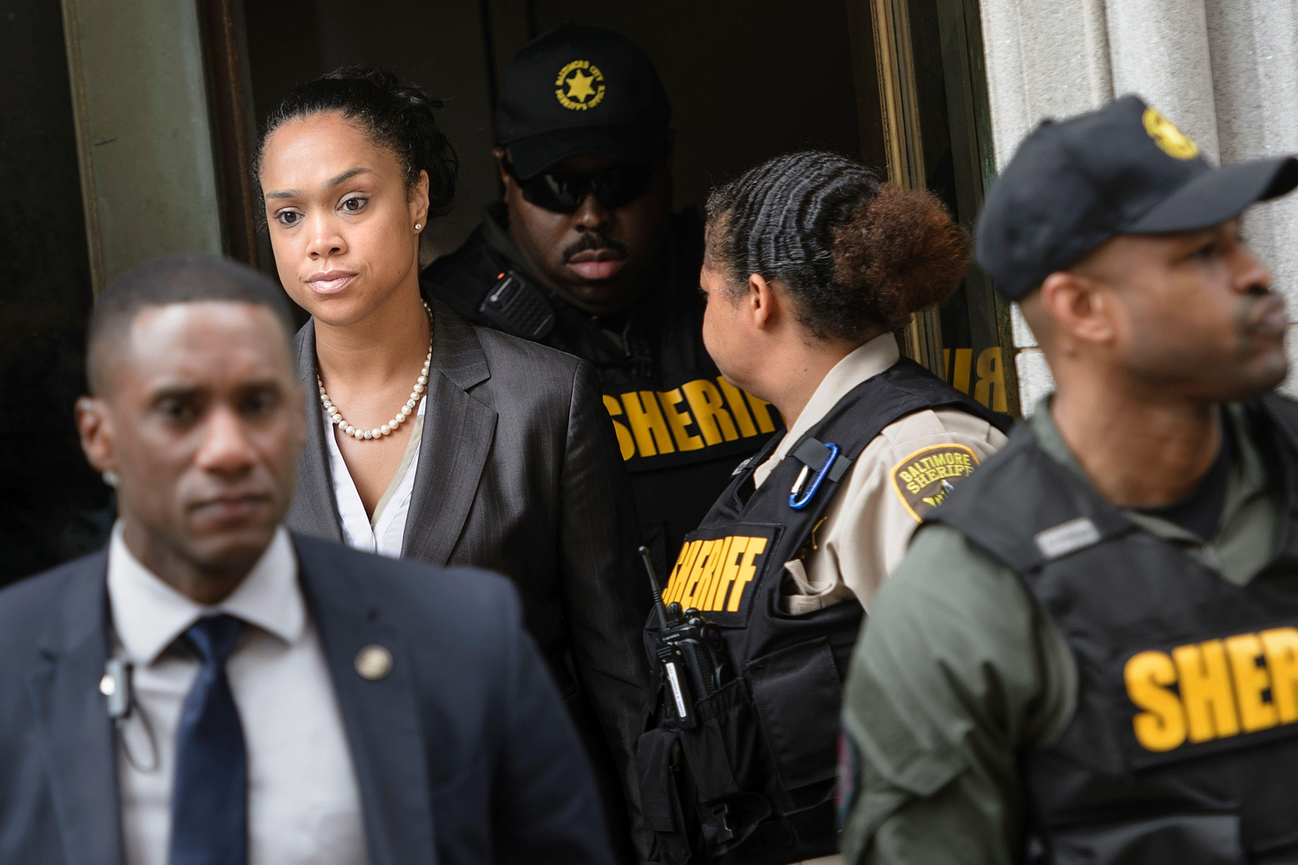 Marilyn Mosby leaves a courthouse surrounded by sheriff's deputies and police