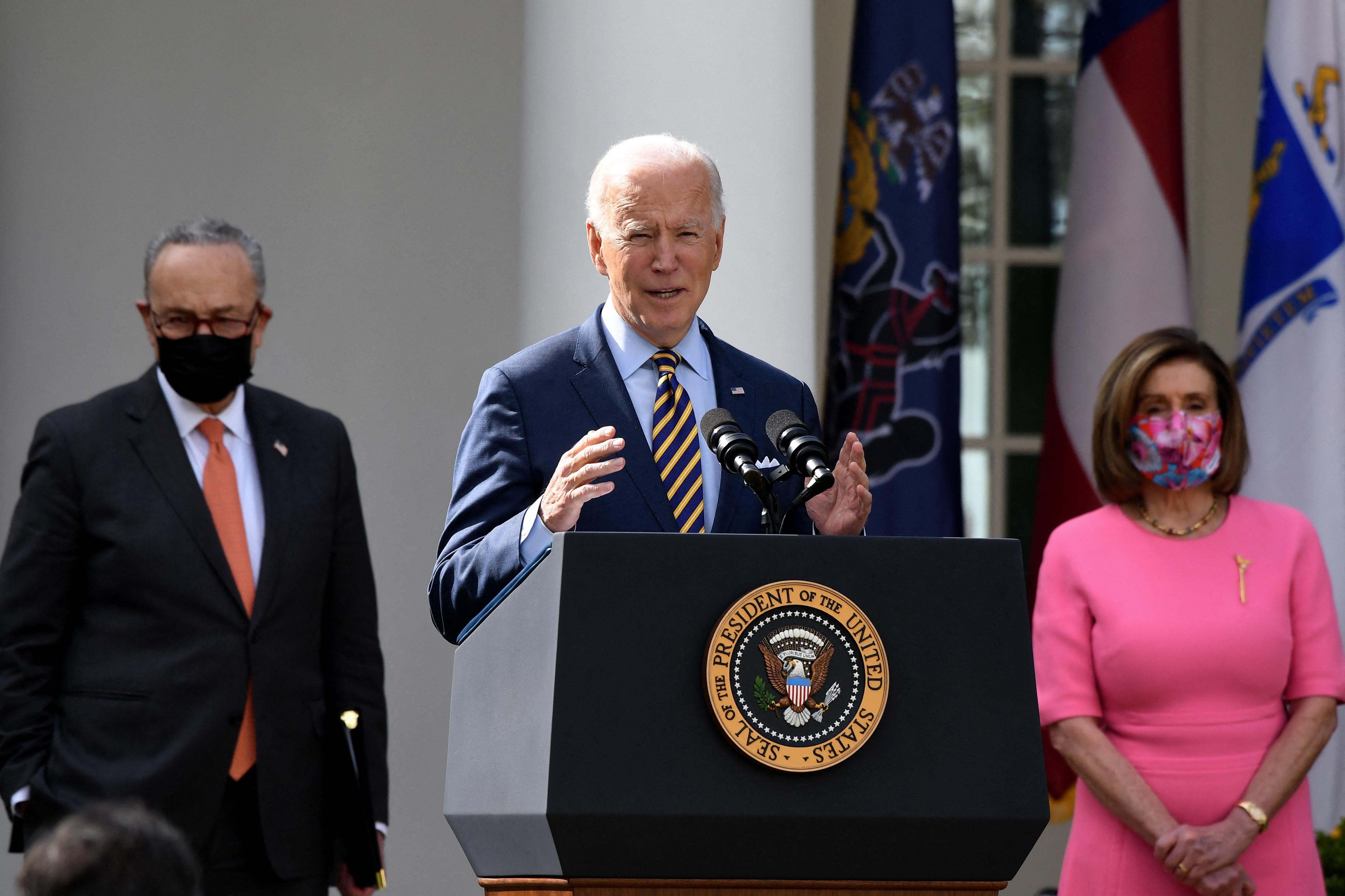 Joe Biden speaks as Chuck Schumer and Nancy Pelosi look on at an event in the White House Rose Garden. 