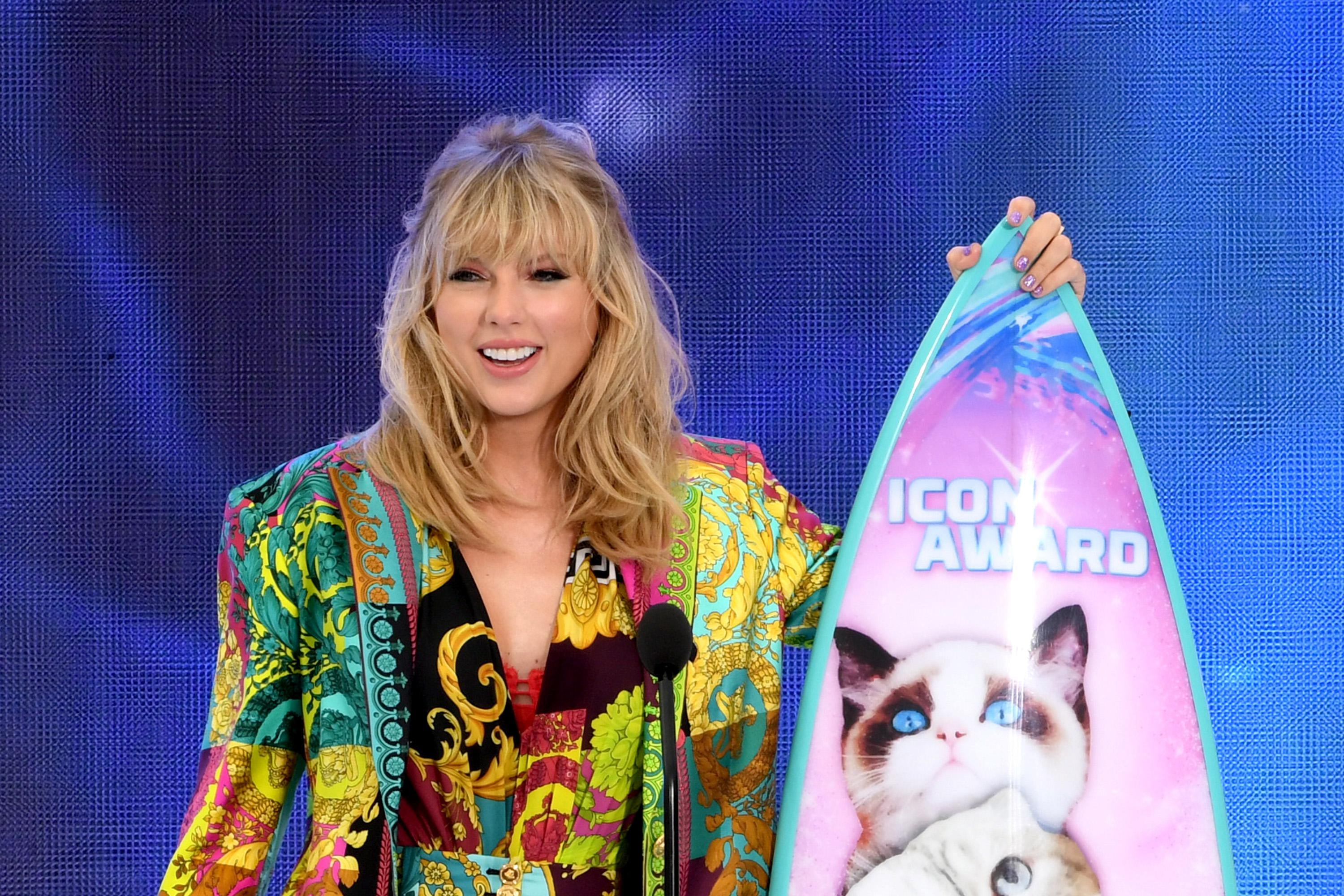 Taylor Swift holds a cat-covered surfboard.