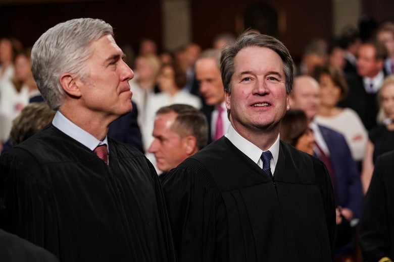 Neil Gorsuch and Brett Kavanaugh smile and stand in judicial robes.