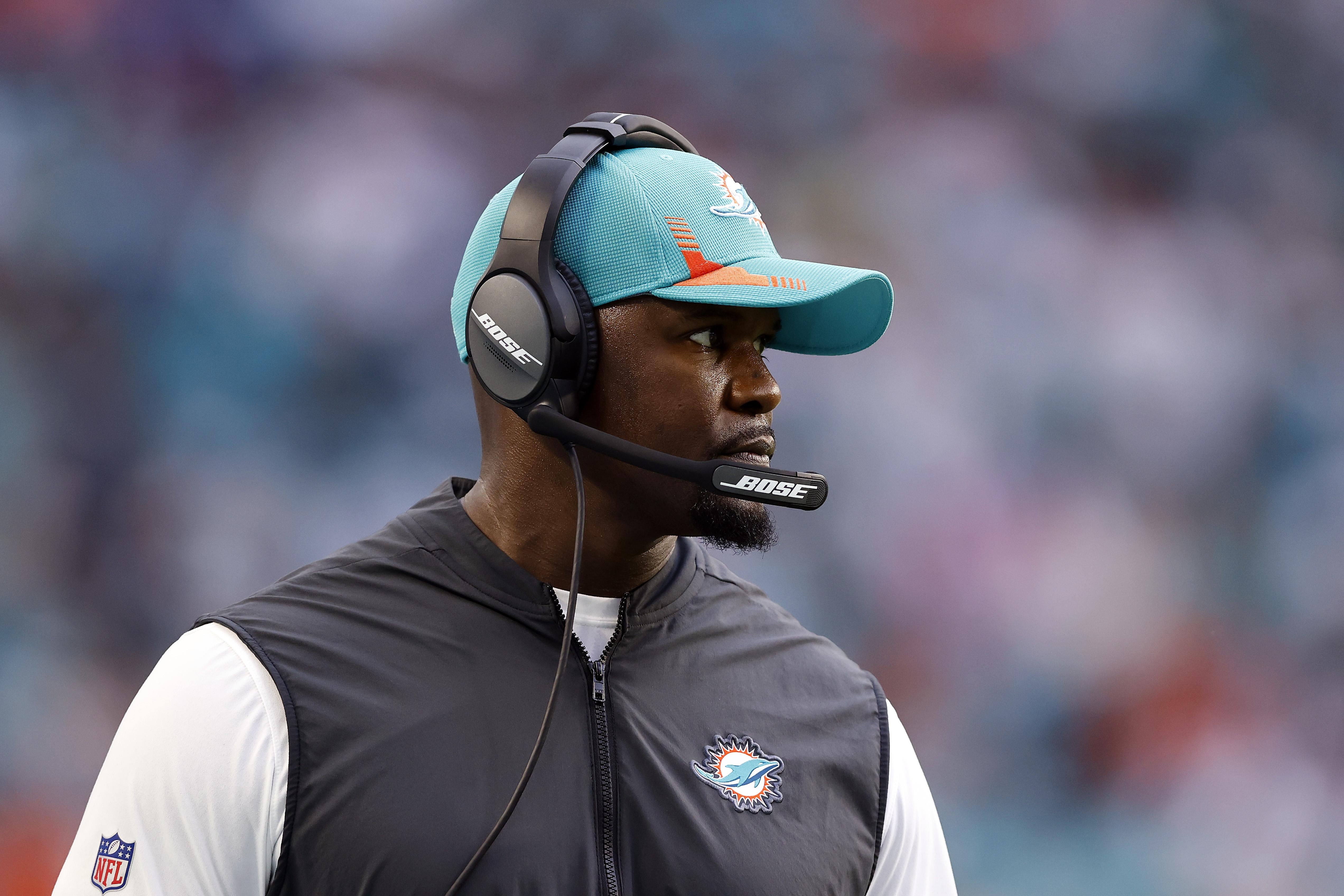 Flores with a Miami Dolphins hat and headset on, on the sidelines.
