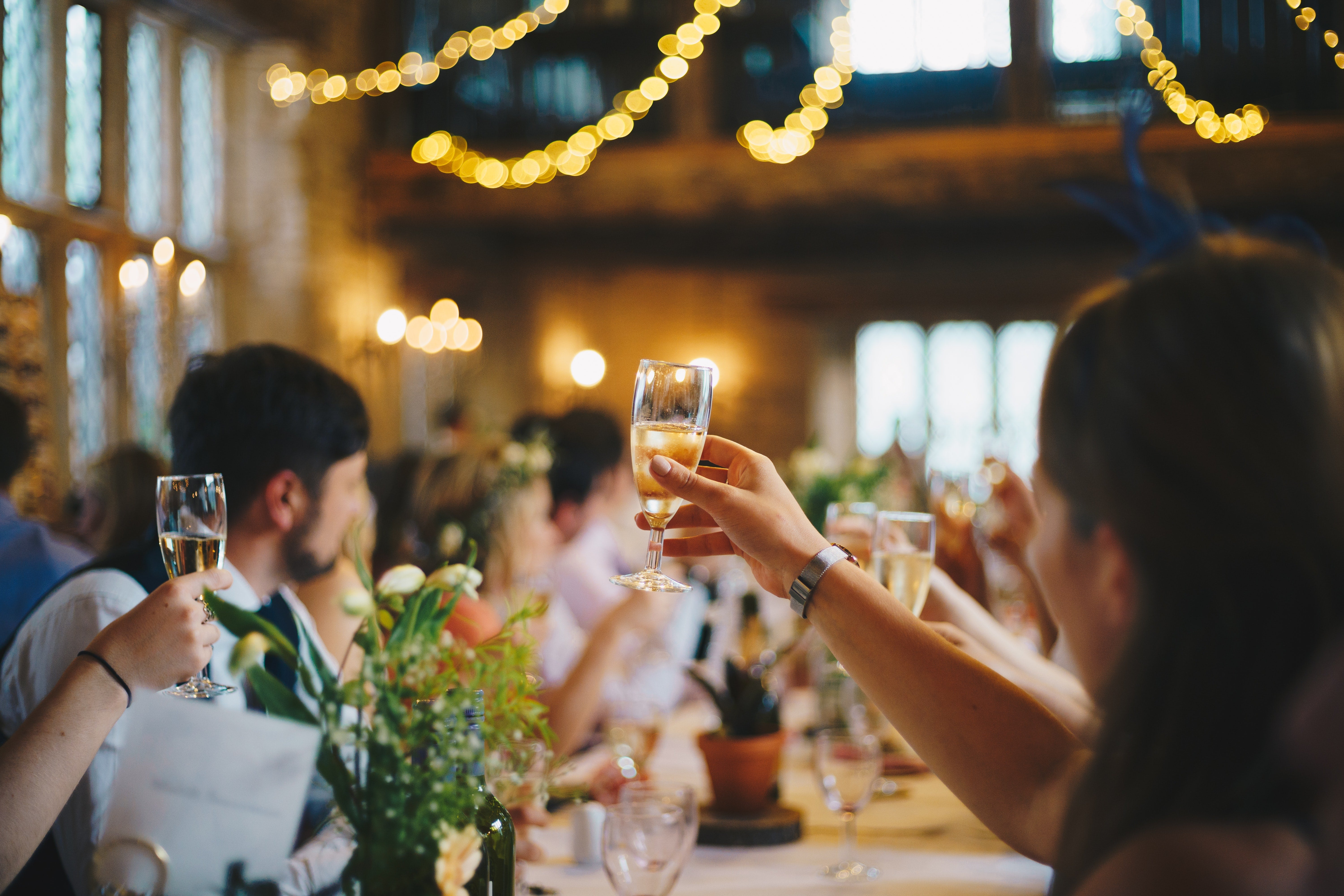 Wedding guests seated in a banquet hall toast the couple