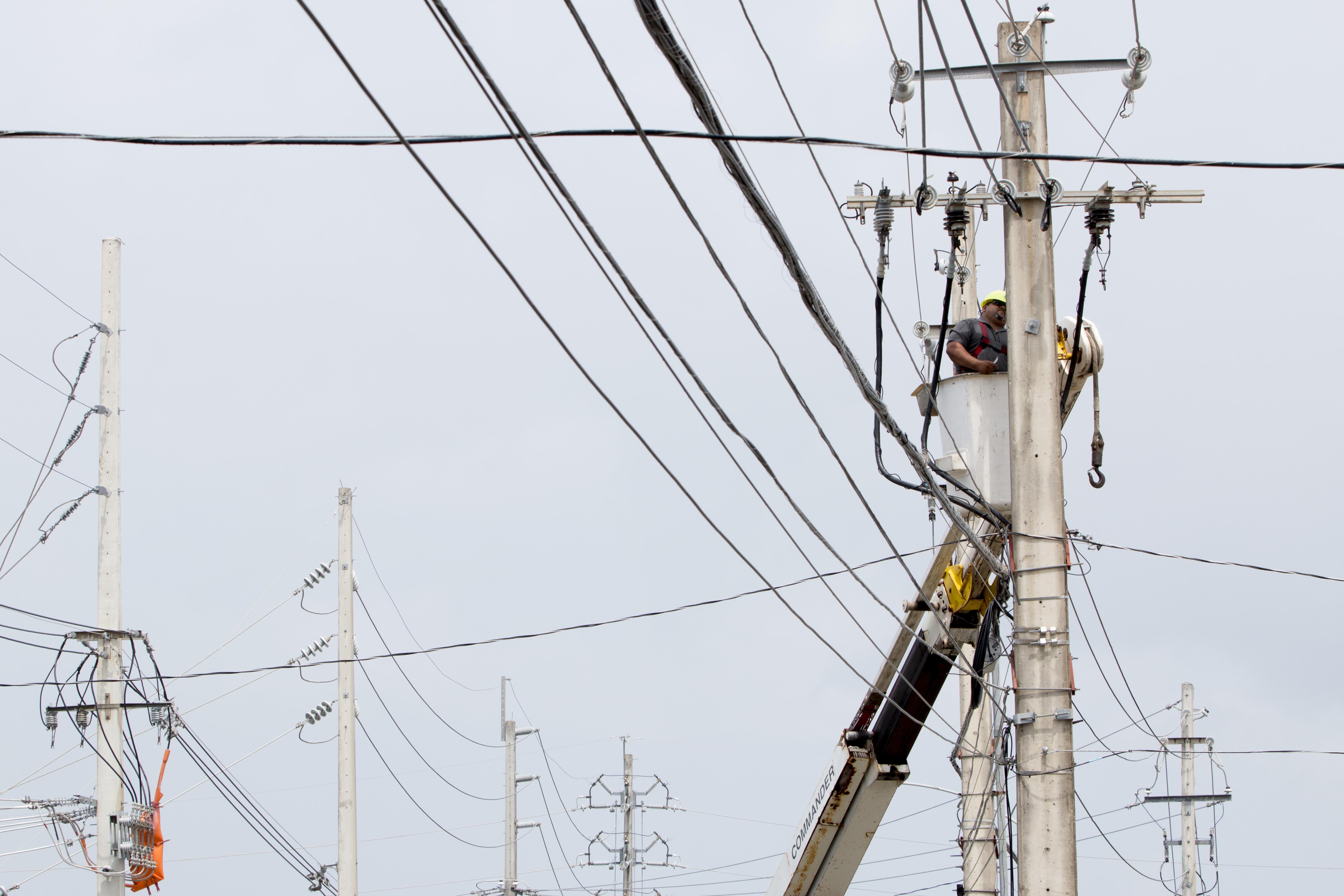 An employee of the Puerto Rico Electric Power Authority repairs a power line damaged by Hurricane Maria.