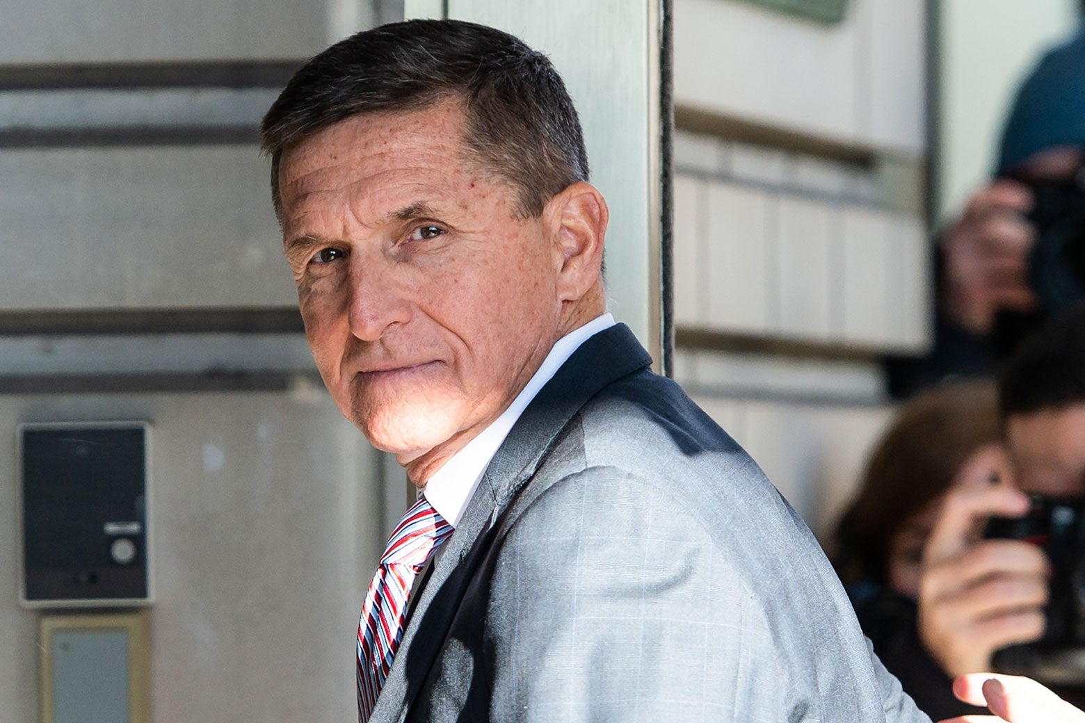 Outside the court building, Flynn turns to the camera, with more photographers in the background