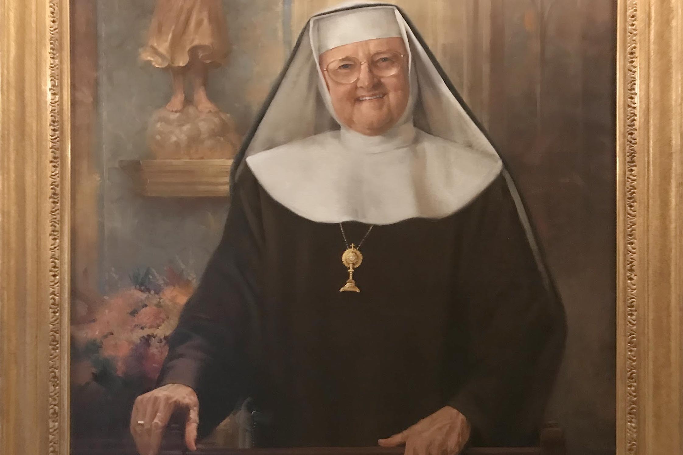 Painting of a nun smiling in a gilded frame on a wall