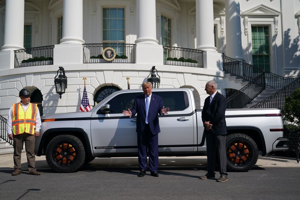 Trump, standing in front of a pickup truck outside the White House, gestures while speaking.