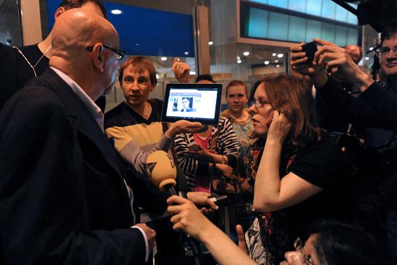 A journalist shows to a passenger a picture of former US spy Edward Snowden on a tablet, at the arrival gate of the Moscow Sheremetevo airport on June 23, 2013. 
