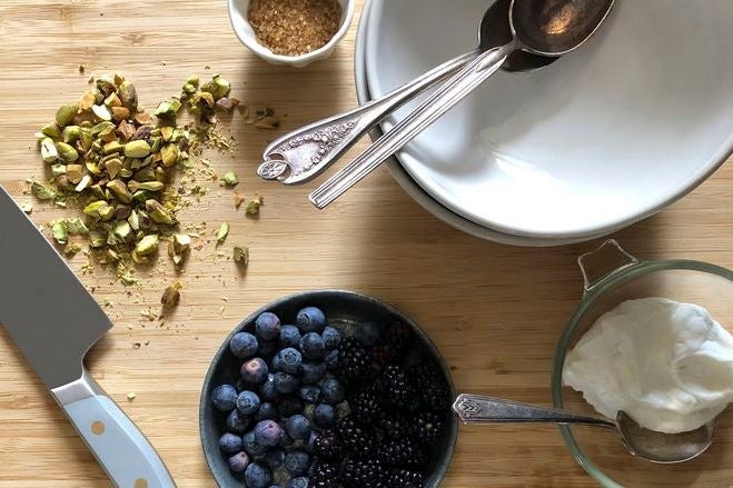 Berries, chopped nuts, and cream on a countertop.