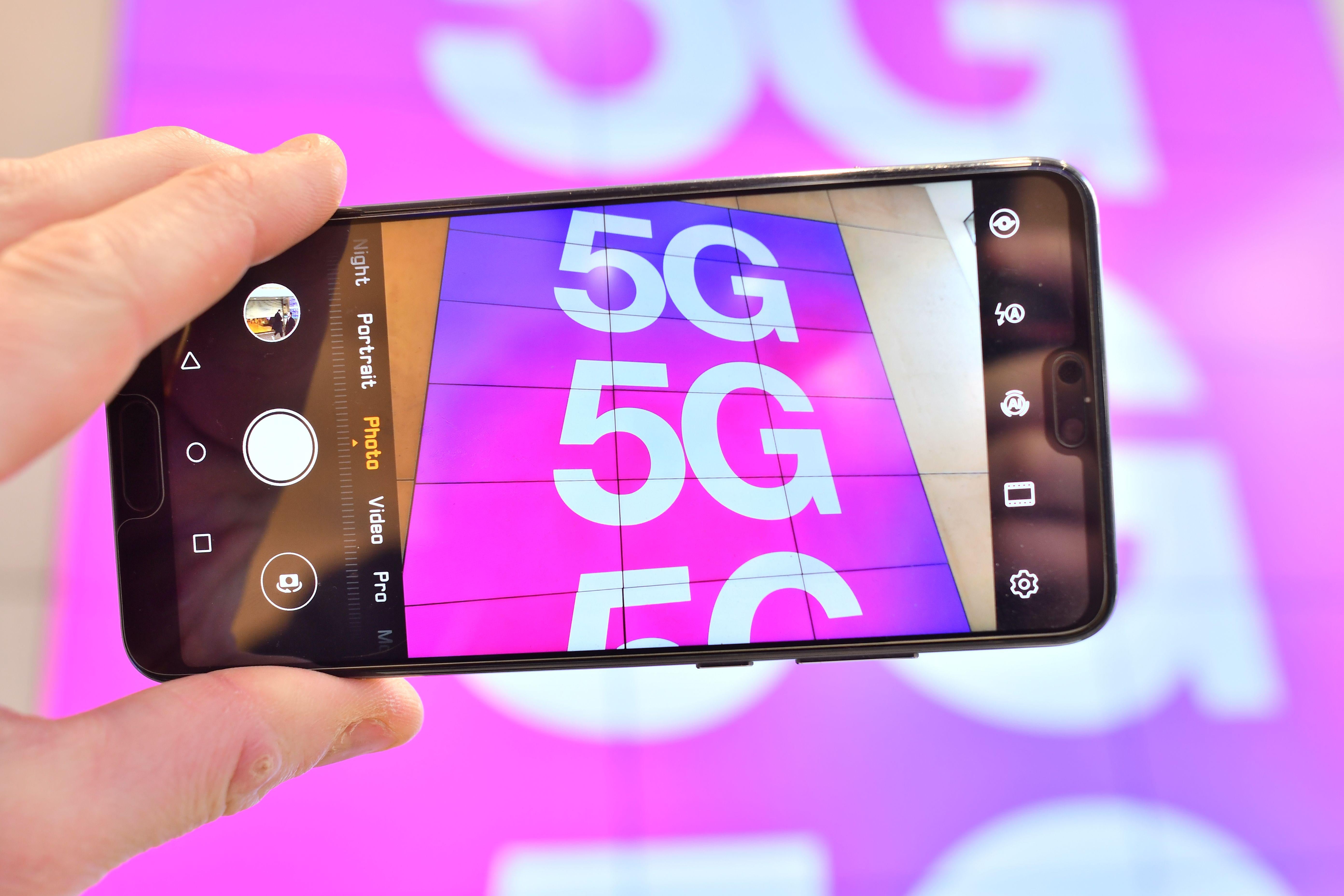 A phone being held up to photograph 5G signage.