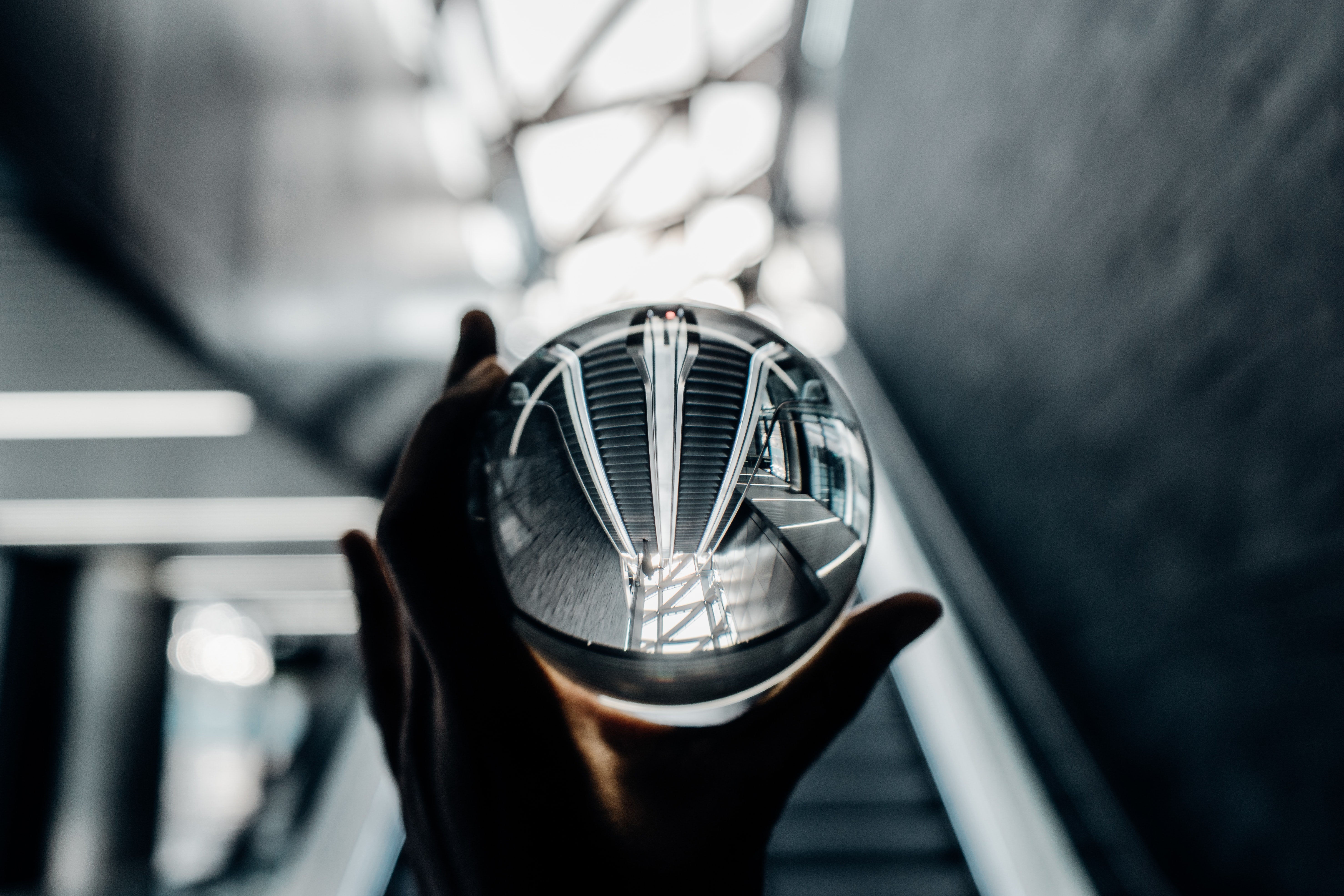 A crystal ball held up to a view of an escalator, inverting it. 