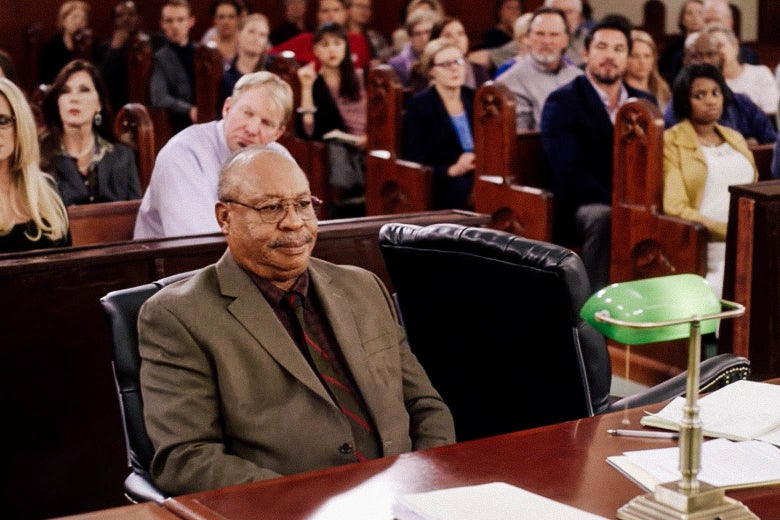 In this still from Gosnell, Earl Billings as Dr. Kermit Gosnell sits behind a table in a courtroom.