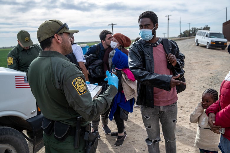 An immigrant man points to a small child as he is confronted by a border officer.